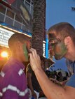 Airman First Class Peter Housewright, 964 AACS, applies camouflage face paint to a child at the T2 sneak preview in Curacao during his deployment supporting counter-drug operations. US Air Force Photo / Senior Airman Joseph Dunk.