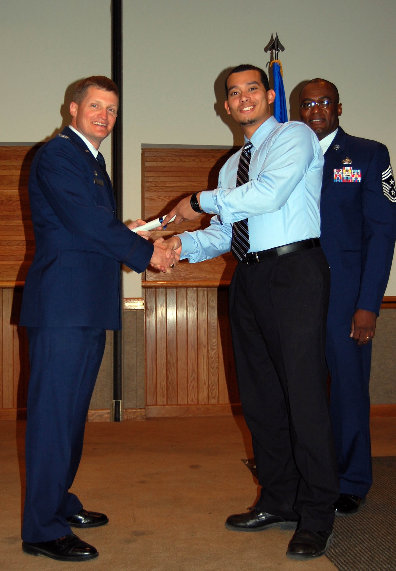 (Middle) Senior Airman Alexander Turner, 926th Group, receives his Associate in Applied Science Degree in Public Health Technology from Col. Howard Belote, 99th Air Base Wing commander (left), during the Community College of the Air Force commencement ceremony here Oct. 27.