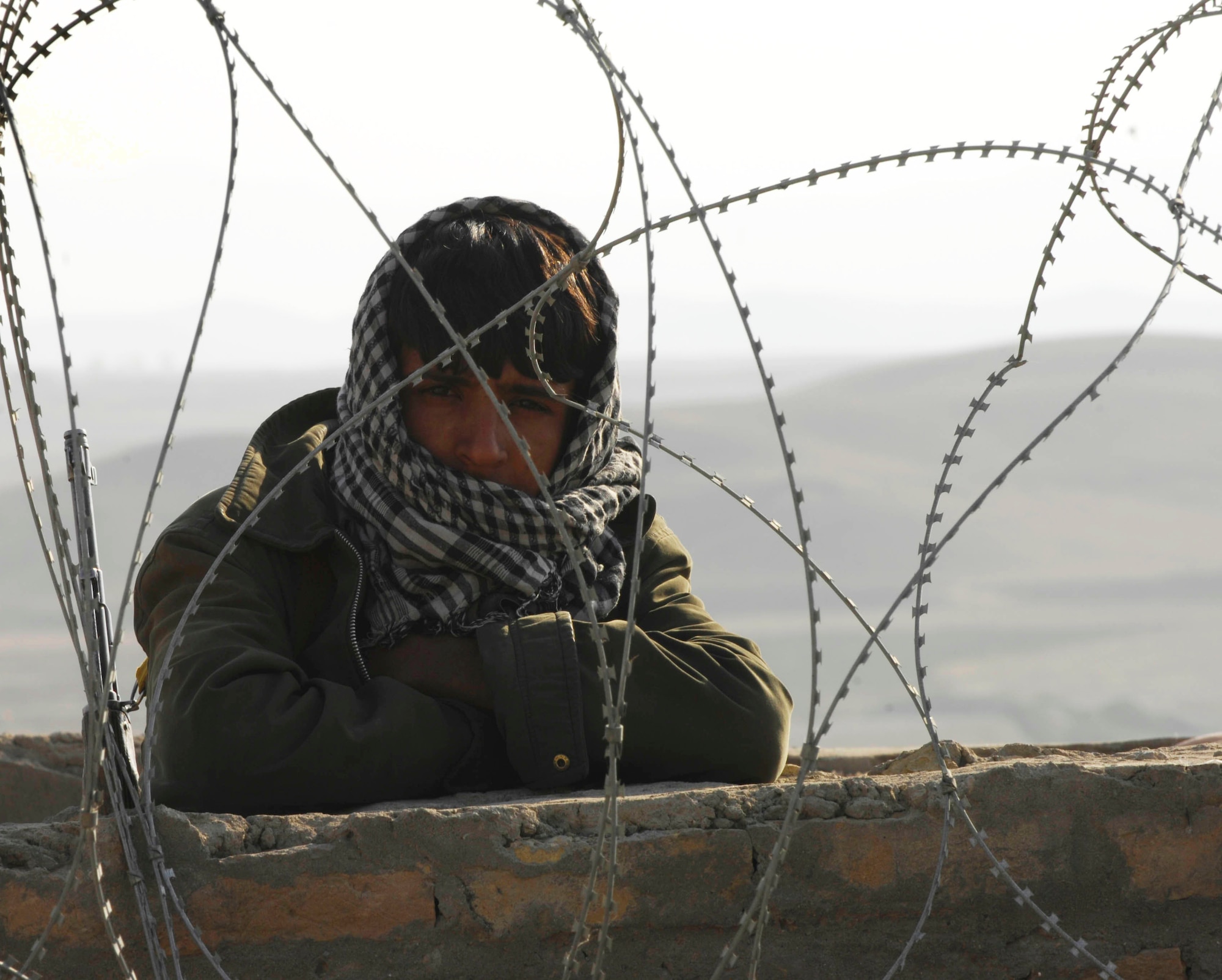 An Afghan guard peers out from behind the walls of a prison in Qalat, Afghanistan.  Security Forces Airmen and Soldiers met with prison officials Oct. 28, 2009, as part of an on-going mission to better the prison and mentor the guards.  (U.S. Air Force photo/Tech. Sgt. Joseph Kapinos)