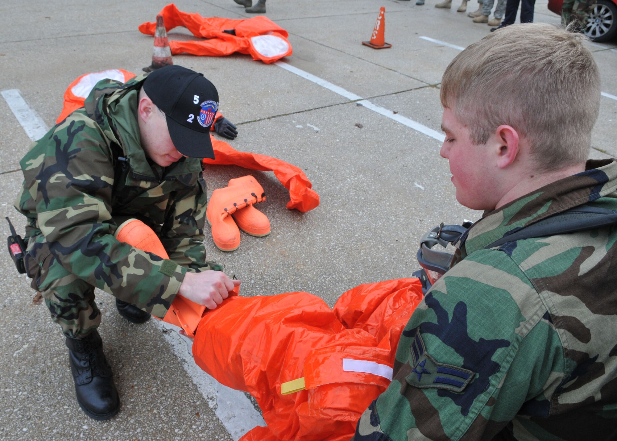 SPANGDAHLEM AIR BASE, Germany -- Staff Sgt. Roy Campos, 52nd Civil Engineer Squadron, assists Airman 1st Class Scott Carrol, 52nd CES, in demonstrating how to put on a class-A hazmat response suit during an on-scene commander's course Oct. 30. The course gave individuals training and certification to be a commander of an incident or work in an emergency operations center. (U.S. Air Force photo/Airman 1st Class Nick Wilson) 