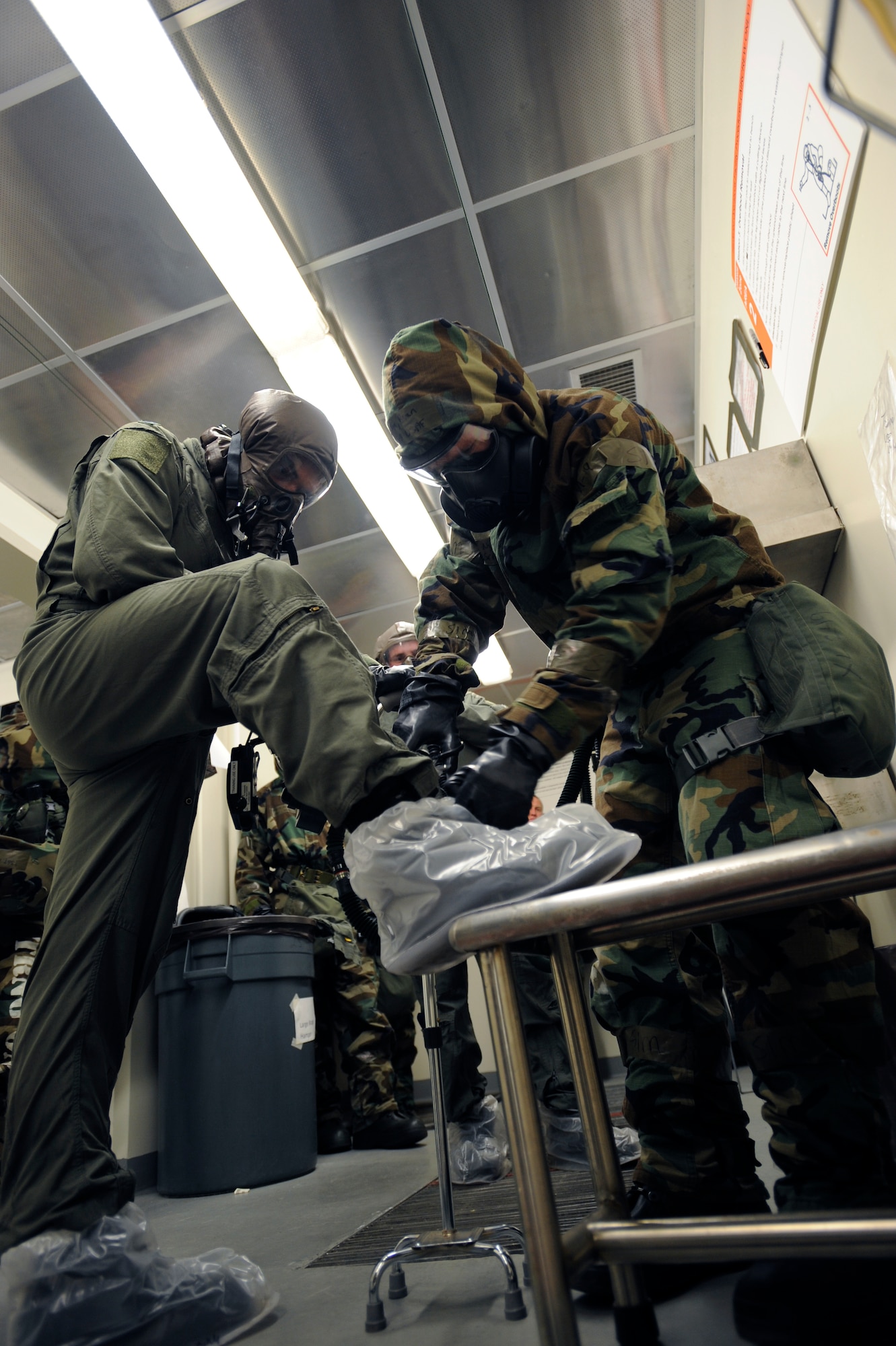 Staff Sgt. Matthew Cost assists Lt. Col. Stephen Renner in removing his booties in a decontamination scenario at the 25th Fighter Squadron during exercise Beverly Midnight 09-02 on Osan Air Base, Nov. 2. (U.S. Air Force photo/Senior Airman Stephenie Wade)