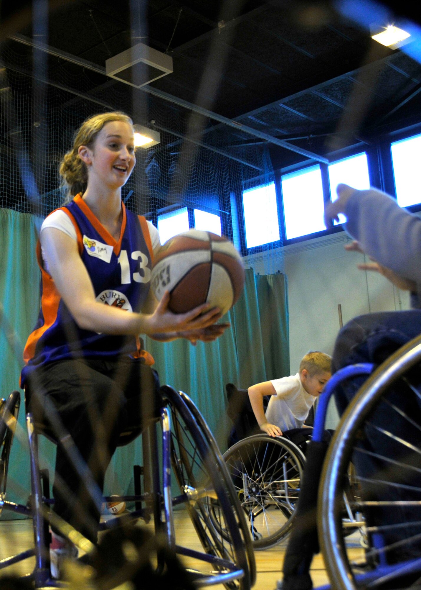 Amy Conroy, Bury Bombers team member, demonstrates to 3rd graders from Lakenheath Elementary how to bounce the basketball in a wheelchair at RAF Lakenheath, England Oct 27. Conroy was a volunteer for a hands-on lesson of wheelchair basketball. (U.S. Air Force photo/Airman 1st Class Eboni knox)