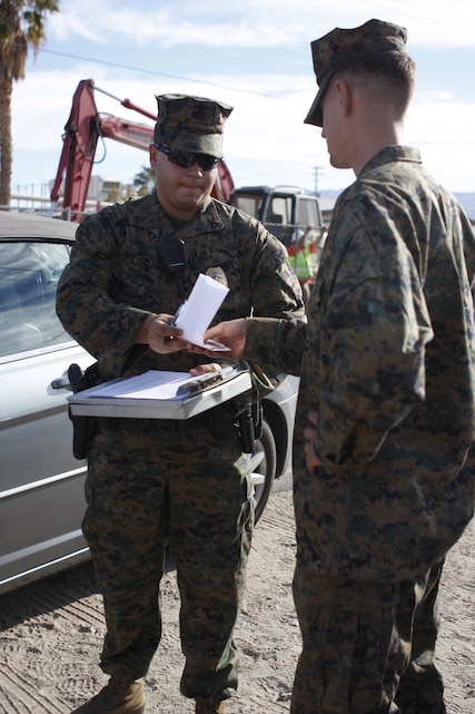Lance Cpl. John Nelson, a military policeman with the Combat Center’s Provost Marshal’s Office, hands paperwork to a Marine involved in an accident Nov. 11. The Accident Investigation branch of PMO determines fault and causes of accidents on and off the installation.