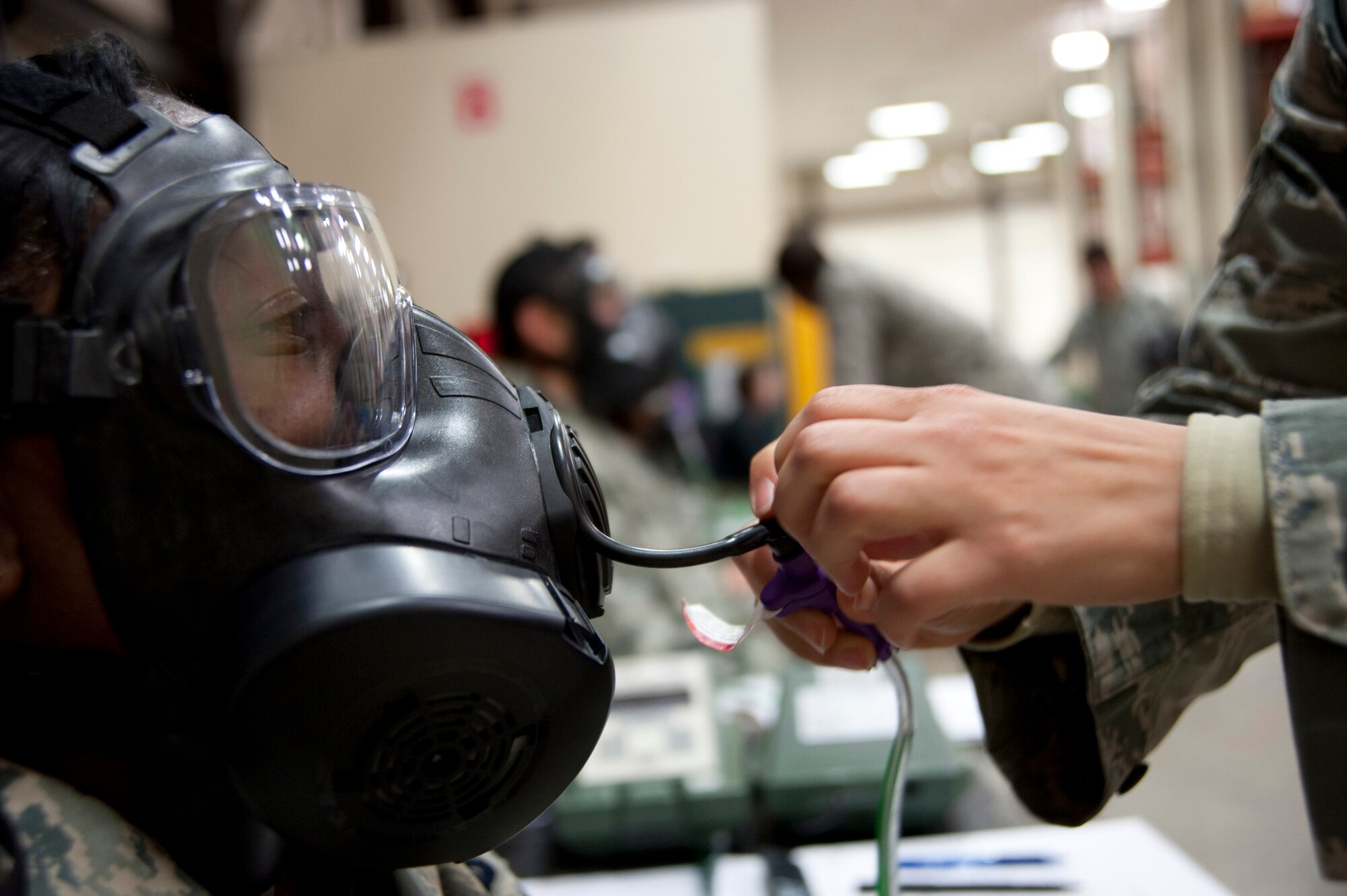 MISAWA AIR BASE, Japan -- Airman 1st Class Estefania Ruvalcaba, 35th Medical Operations Squadron mental health technician, attaches an adapter to the drinking tube of a new M-50 Joint Service General Purpose Mask in the 35th Logistics Readiness Squadron supply warehouse Nov. 3. Airman Ruvalcaba tested how well the mask fit Staff Sgt. Diane Foster by measuring how many outside smoke particles were able to enter the mask. (U.S. Air Force photo/Staff Sgt. Samuel Morse)