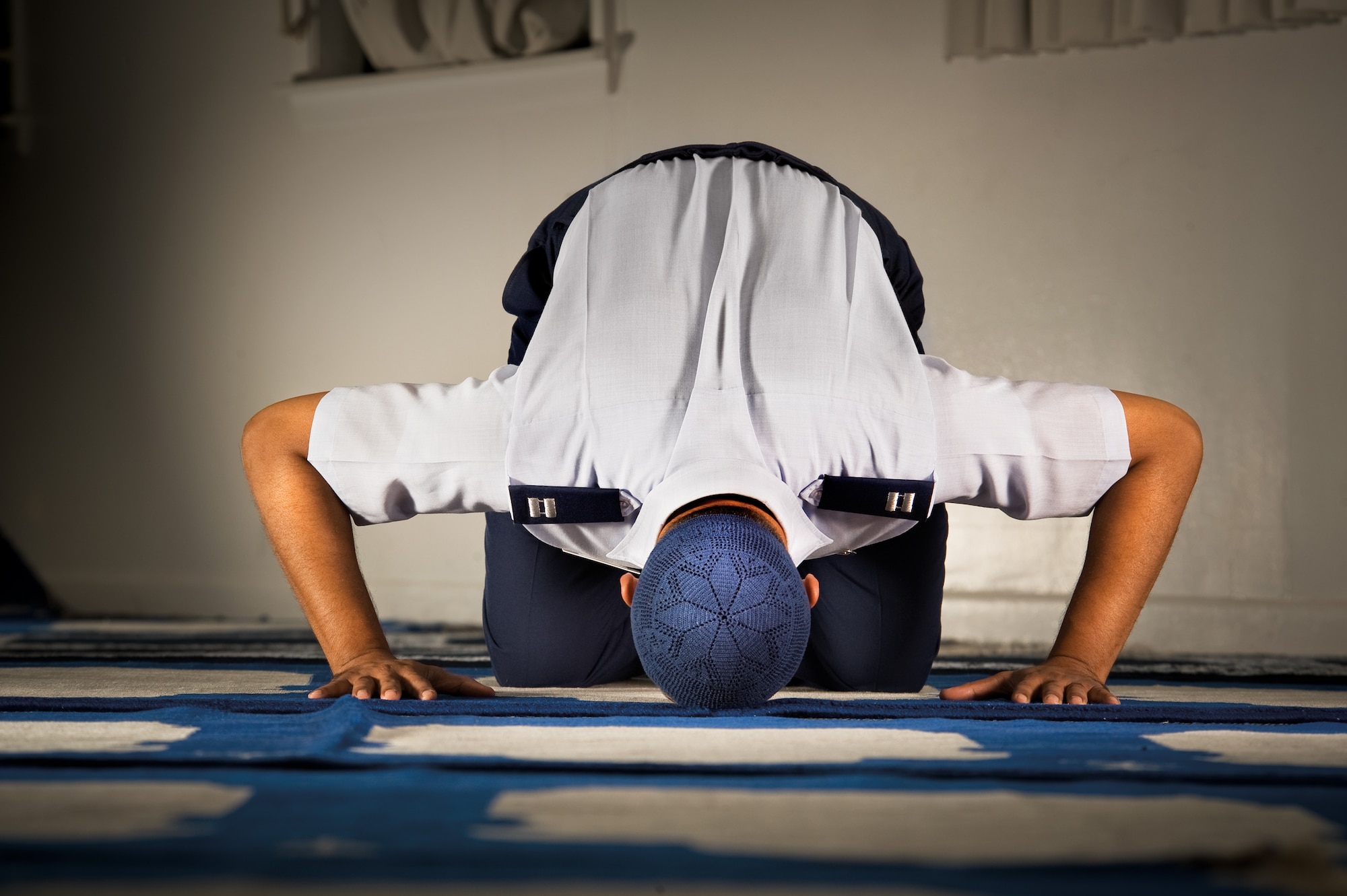 Chaplain (Capt.) Sharior Rahman, an Air Force Imam, holds the sajjud position during salah in the prayer hall of the Defense Language Institute Student Center, Lackland AFB, Texas. The center sees as a many as 550 people each Friday. (U.S. Air Force photo/Lance Cheung)
