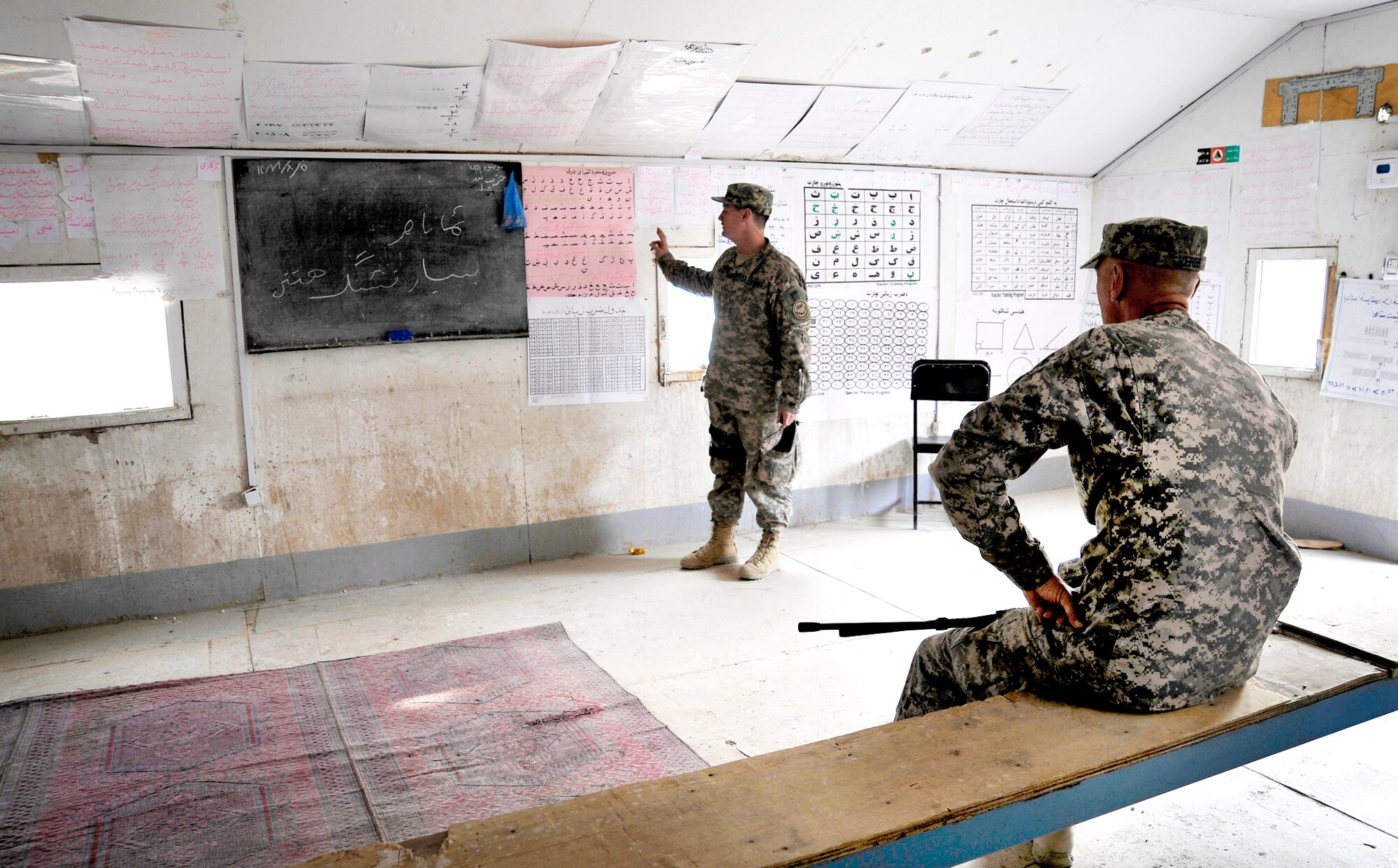 Lt. Col. Andy Veres listens to Maj. J.D. Loftis speak about Afghans' learning material in a classroom Oct. 27, 2009, in Qalat, Afghanistan. Colonel Veres is the Zabul Provincial Reconstruction Team commander, and Major Loftis is an information operations officer from the PRT. (U.S. Air Force photo/Staff Sgt. Angelita Lawrence) 