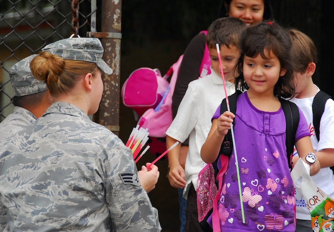 Stacey Scott takes a glow-in-dark necklace to wear for staying visible during Halloween from Senior Airman Meagan Bustillo at the Lamb's Elementary School gate here Oct. 30. The 437th Airlift Wing Safety Office performs annual safety sendoffs for local students to remind them to stay safe while trick-or-treating. Airman Bustillo is a safety apprentice with the 437 AW Safety Office and Stacey is the daughter of Master Sgt. Donald Scott who is with the 437th Maintenance Operations Squadron. (U.S. Air Force photo/Staff Sgt. Daniel Bowles)