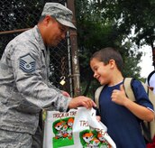 Master Sgt. Erwin Arguilla gives Alex Serrano a colorful trick-or-treat bag at the Lamb's Elementary School gate here Oct. 30. Members of the 437th Airlift Wing Safety Office provided students passing through both the Lamb's and Hunley Park Elementary School gates free bags for collecting Halloween candy and reminded each to have a safe Halloween. Sergeant Arguilla is the 437 AW Safety Office ground safety superintendent and Alex is the son of Staff Sgt. Kevin Serrano who is with the 437th Logistics Readiness Squadron. (U.S. Air Force photo/Staff Sgt. Daniel Bowles)