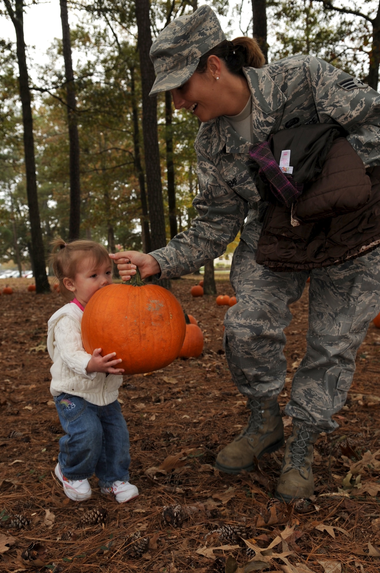 Senior Airman Anne Kemp, 4th Force Support Squadron force management operation technician, helps her daughter Autumn, 20 months old, carry a pumpkin from the child development center's annual pumpkin patch on Seymour Johnson Air Force Base, N.C., Oct. 30, 2009. The pumpkin patch, totaling 350 pumpkins, was open to children enrolled at the CDC, youth center, family child care and children of deployed military members. (U.S. Air Force photo/Senior Airman Courtney Richardson)