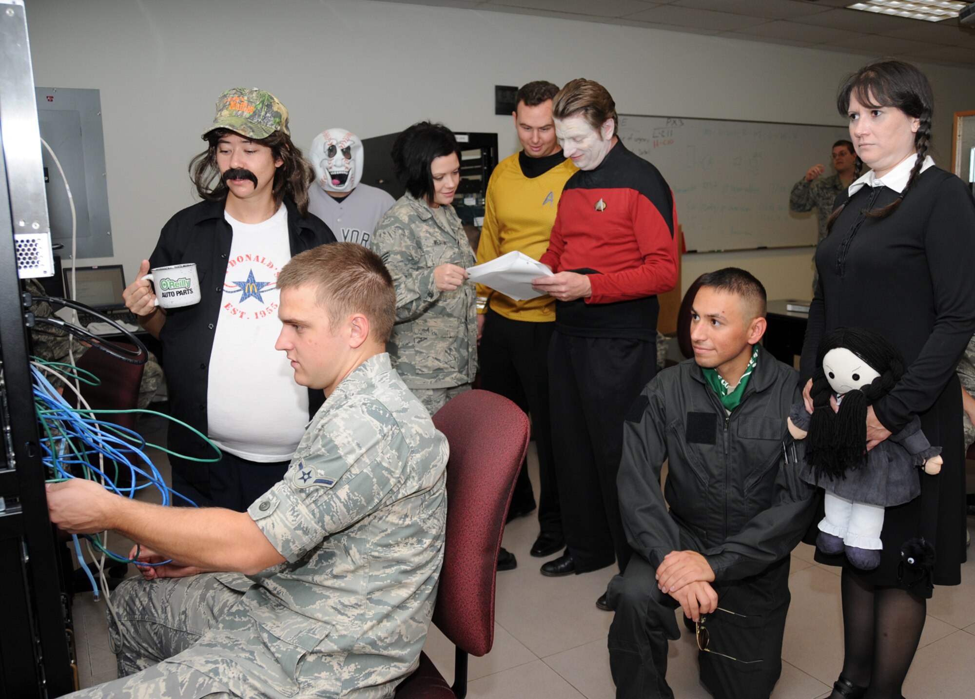 Airman Nathan Lascek and Staff Sgt. Dody Weather, in battle dress uniforms, students in the 338th Training Squadron’s computer maintenance training flight, are surrounded by instructors who got into the Halloween spirit for classes Oct. 30.  From left, instructors are Staff Sgt. Sarah Rogers (mechanic), Jason Viglione (baseball), Shane Reynolds (Captain Kirk from Star Trek), civilian Daniel Baumgartner (Data from Star Trek), Staff Sgt. Jose Ramos (pilot) and Gina Duncan (Wednesday from the Adams Family).  (U.S. Air Force photo by Kemberly Groue)