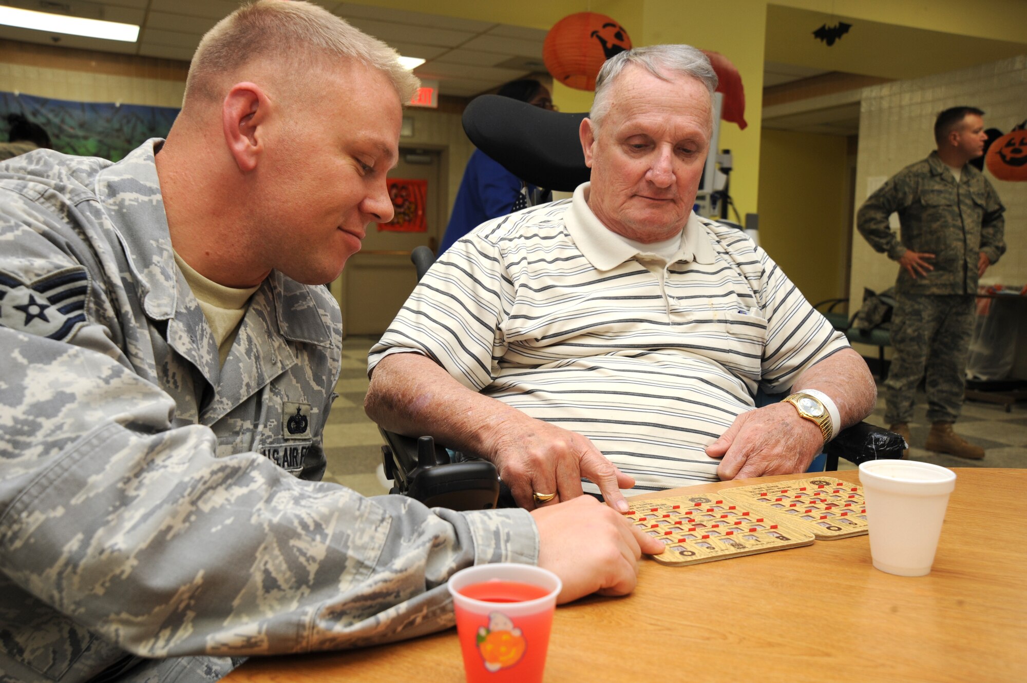 Staff Sgt. Ryan Overcash, 22nd Security Forces Squadron, helps Bill Harrington search for numbers, Oct. 29, 2009, during a bingo game at the Robert J. Dole Department of Veterans Affairs Medical and Regional Office Center, Wichita, Kan. Every month Team McConnell members host VA bingo at the center. Route 56 hosted this game. (U.S. Air Force photo by Tech. Sgt. Chyrece Campbell)