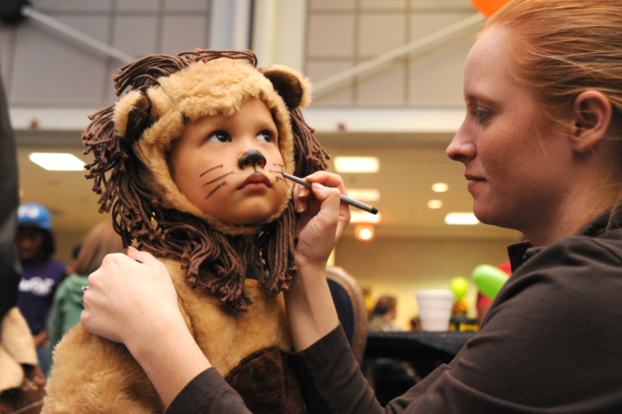 Stephen DeGuzman Jr., 3, 22nd Force Support Squadron family member, stands still as his mother Grace DeGuzman adds finishing touches to his lion costume during Neowallah Ball at McConnell Air Force Base, Kan., Oct. 30, 2009.  Interested participants had their photos taken for free. Ball goers also had chances to win door prizes throughout the night. (U.S. Air Force photo by Tech. Sgt. Chyrece Campbell)