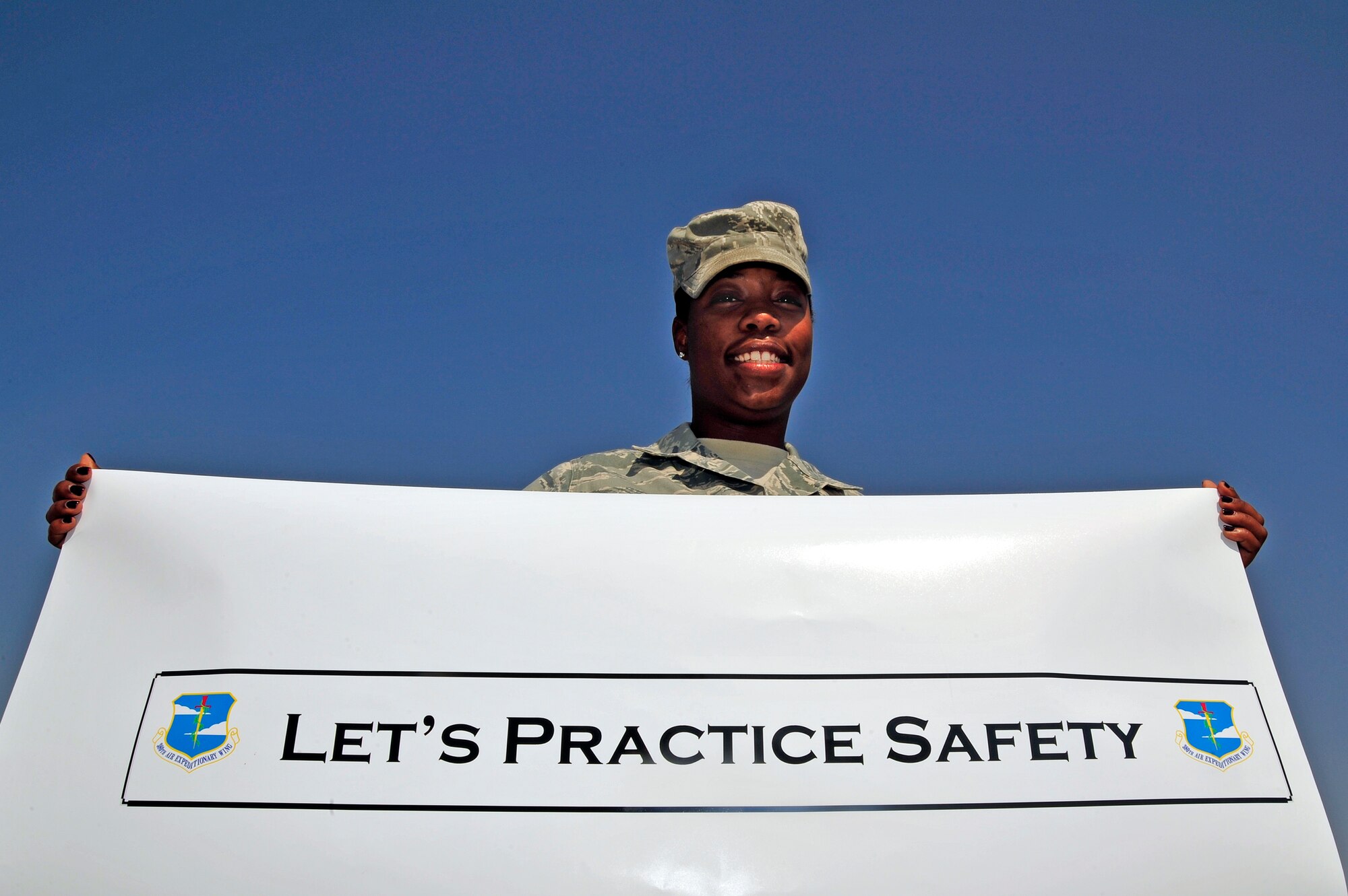 SOUTHWEST ASIA -Senior Airman Patisha Johnson, 380th Expeditionary Security Forces Squadron, holds a sign Nov. 3, 2009 at a gate reminding Airmen to be safe. Airman Johnson is currently deployed from MacDill Air Force base, Fla., and grew up in Orlando, Fla. (U.S. Air Force photo/Tech. Sgt. Charles Larkin Sr)