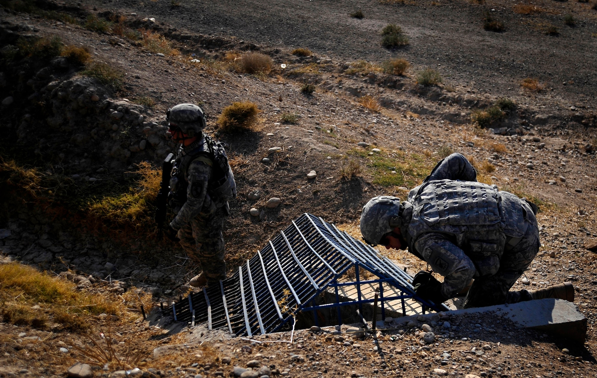 U.S. Army Sgt. William Brinkley, a security forces Soldier, assigned to the Provincial Reconstruction Team (PRT) Zabul, stands guard while U.S. Air Force Capt. Rick Vermillion, PRT engineer,  inspects a bridge for improvised explosives devices, damages, or traces of tampering here Oct. 23, 2009.  The inspections provide safety to the people of Zabul as well as coalition forces while traveling. (U.S. Air Force photo/Staff Sgt. Angelita Lawrence)