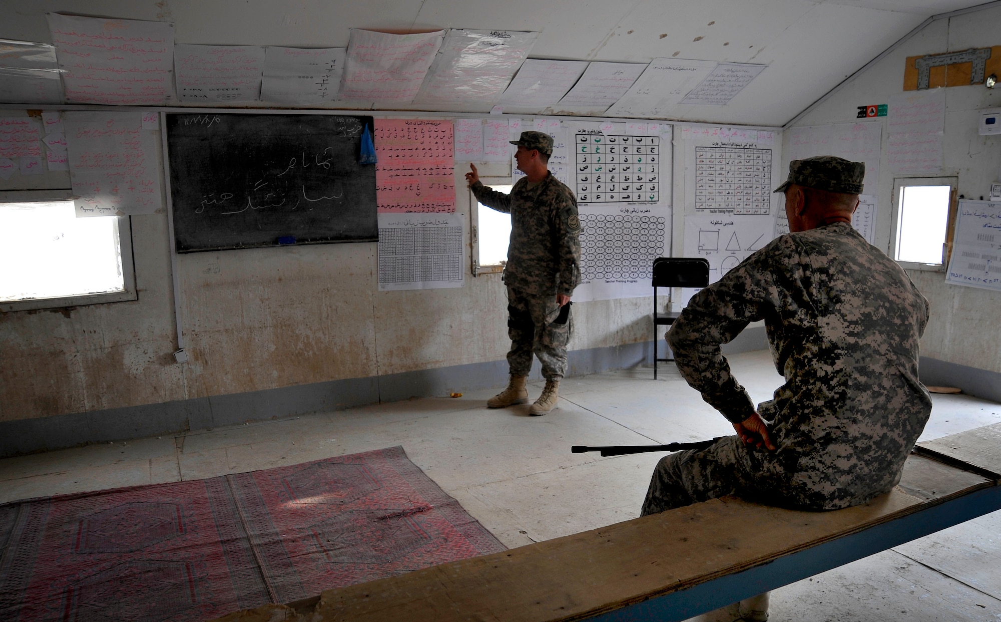U.S. Air Force Lt. Col. Andy Veres, Commander of the Provincial Reconstruction Team Zabul,  listens to Maj. J.D. Loftis, an information operations officer from the PRT, speak about Afghan's  learning material in a classroom in Qalat Oct. 27, 2009.  (U.S. Air Force photo/Staff Sgt. Angelita Lawrence)