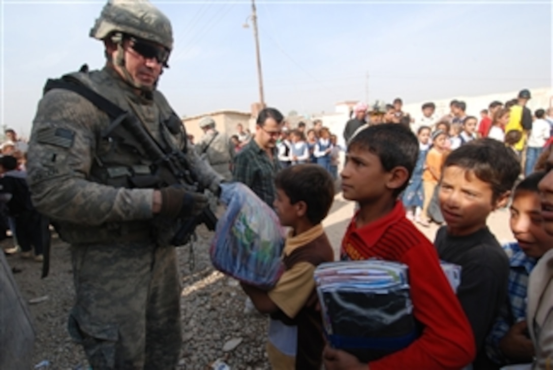 U.S. Army 1st Lt. George Gordon, assigned to Outlaw Platoon, Alpha Battery, 2nd Battalion, 82nd Field Artillery Regiment, 3rd Brigade Combat Team, 1st Cavalry Division, hands out backpacks to children at an education assistance drop at Dexebtoth village north of Mosul, Iraq, on Oct. 25, 2009.  