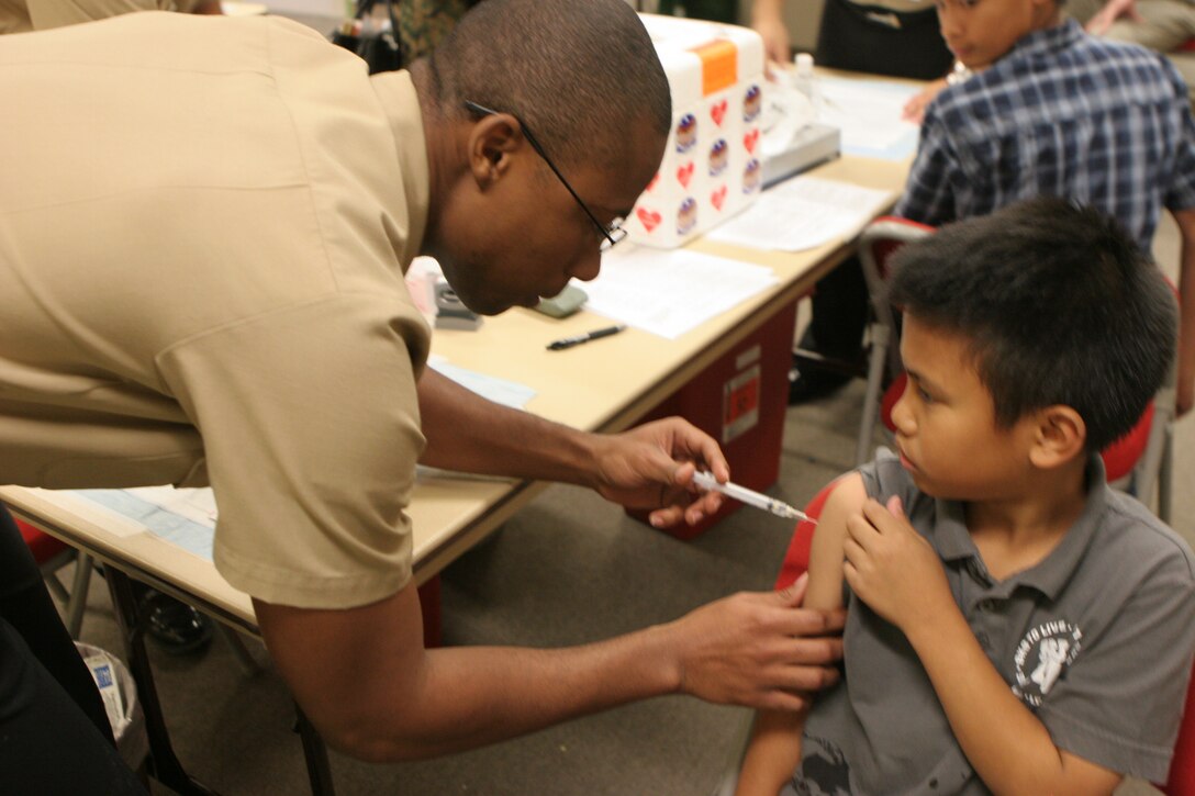 A corpsman with Naval Hospital Camp Pendleton injects the H1N1 vaccination to James, 8, from the Philippines, at the NHCP, Nov. 3. Eligible TRICARE beneficiaries will be able to receive the H1N1 vaccination through a shot or a nasal FluMist, while service members must receive theirs by shot only. Vaccinations for Marines and sailors are expected to be available in a few weeks. Vaccinations for high-risk family members began Nov. 2.