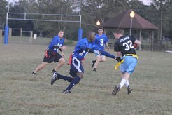 A member of the Coast Guard flag football team reaches to remove the flag from Ross Stegner as he runs the ball on a punt return during an intramural game here Nov. 3. The 437th Security Forces Squadron defeated the Coast Guard 20-6. Cook is a member of the 437 SFS. (U.S. Air Force photo/Staff Sgt. Marie Brown)