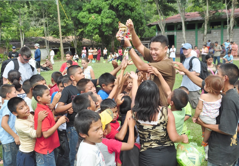 SOTO CANO AIR BASE, Honduras – Air Force Staff Sgt. Song Moon, medical element pharmacy NCO in charge, hands some candy out to children of El Ciruelo, a remote mountain village near Comayagua, Honduras, Oct 31 for a monthly chapel hike. Eighty-one volunteers from Joint Task Force-Bravo hiked more than five miles up and down a rocky, mountain road to deliver food to the remote village. The volunteers carried a total of 122 bags of food, equaling 2,684 pounds. Each bag of food was intended to go to one of the families of this poor mountain village, and included vegetable oil, ketchup, pasta, a couple cans of sardines and bags of sugar, rice, flour and beans (U.S. Air Force photo/Staff Sgt. Chad Thompson).