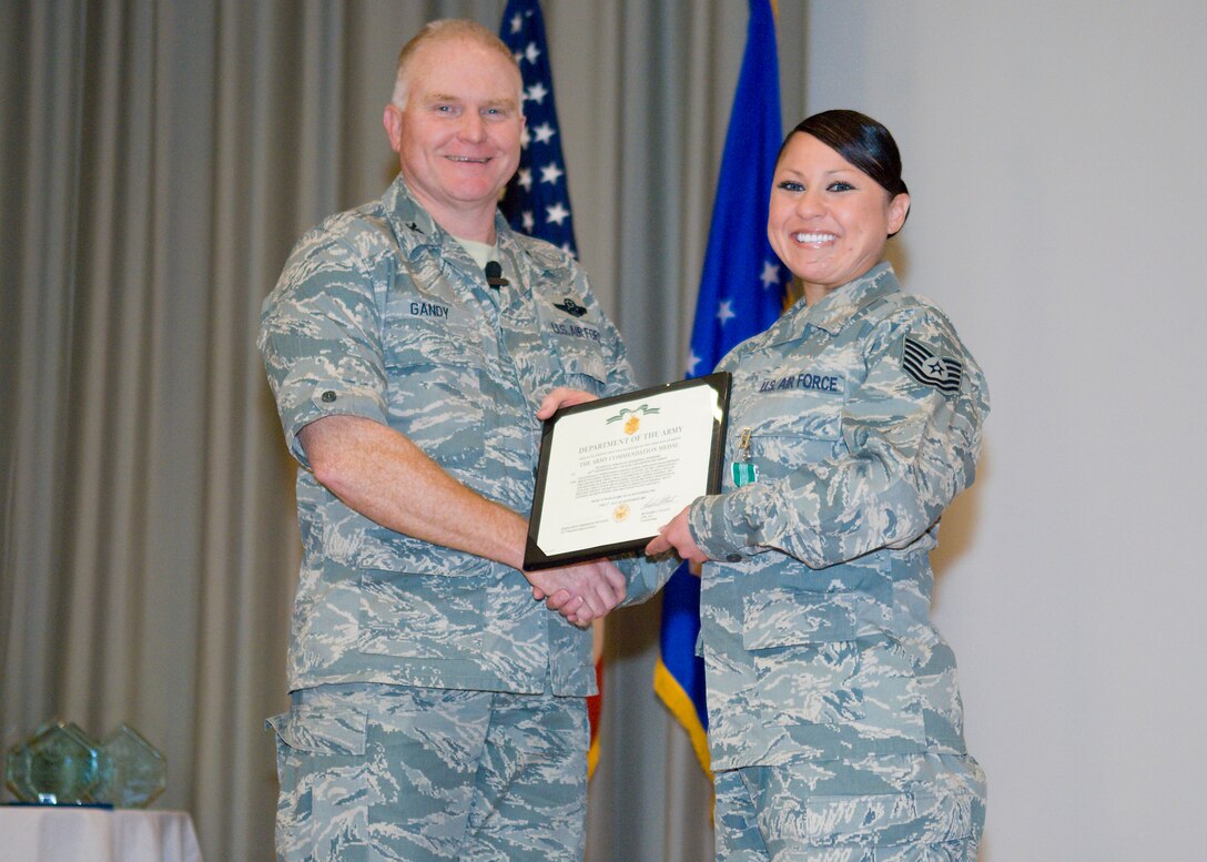 Col. Jerry Gandy, 95th Air Base Wing commander, presents Tech. Sgt. Jennifer Marrero with the Army Commendation Medal during a commander's call in the base theater Oct. 29. Sergeant Marrero received the medal for her accomplishments during OPERATION IRAQI FREEDOM in September 2009. (Air Force photo/Mike Cassidy)