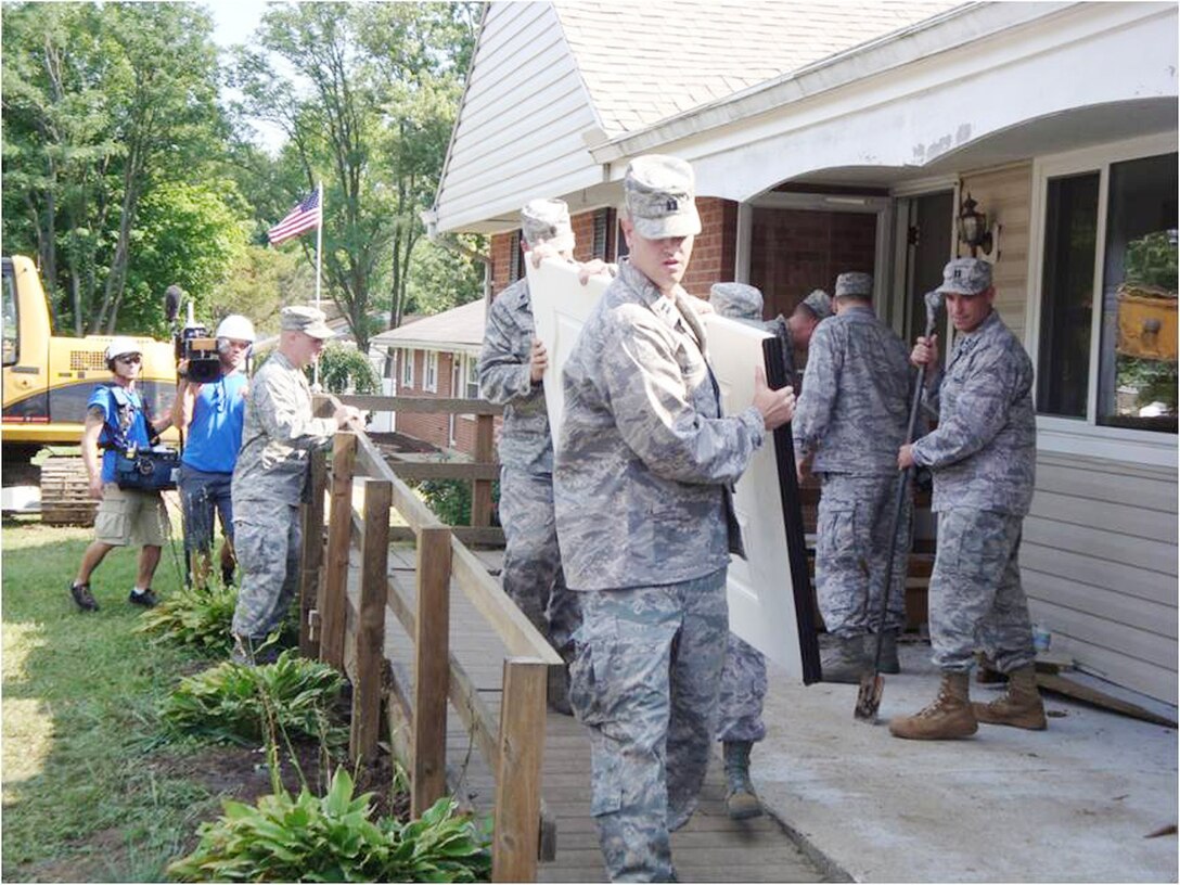 Air Force volunteers carry out a door, as camera crews tape the demolition of James Terpenning's house Aug. 1, 2009, for an episode of 'Extreme Makeover: Home Edition.' About 25 Air Force military members and civilians volunteered a Saturday morning to help with the demolition of the Terpenning family home. The episode featuring the family's re-built house will air Nov. 8 on ABC at 8 p.m./7 p.m. Central time. (U.S. Air Force photo/Ron Fry) 