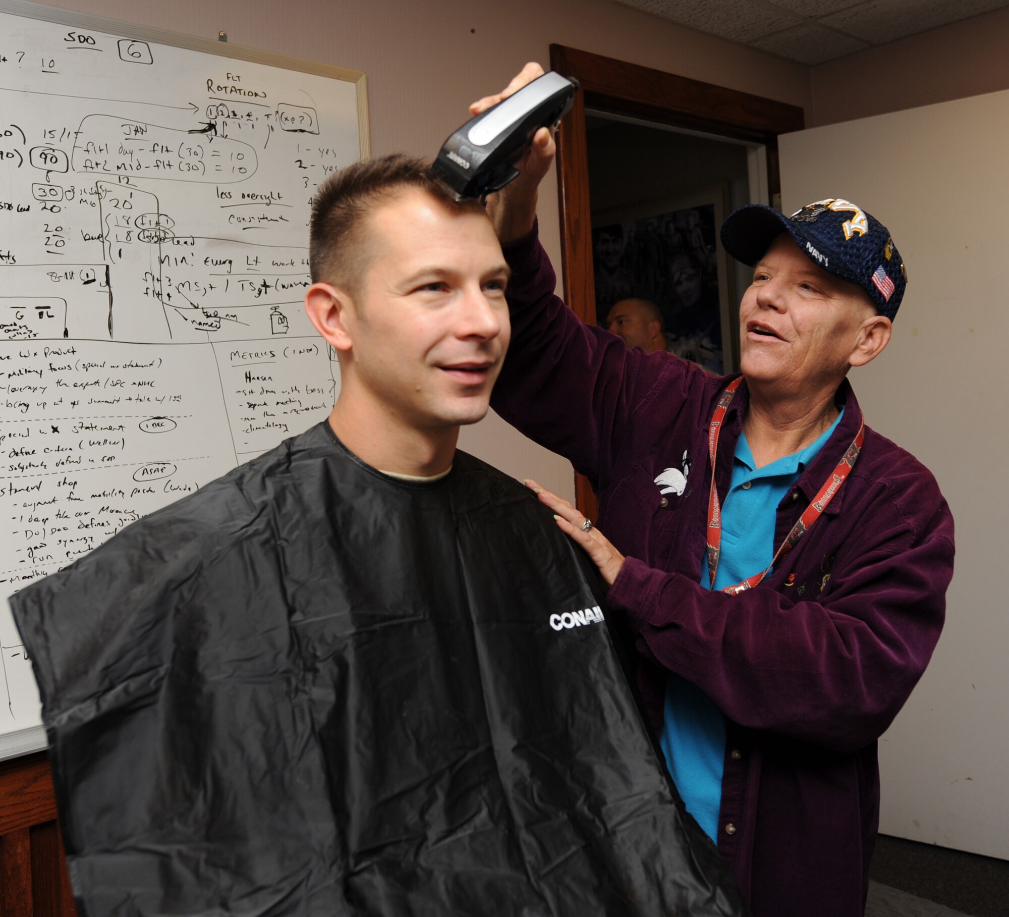 Lt. Col. Timothy Dreifke, 26th Operational Weather Squadron, commander, gets his head shaved by Mary Eveld, 26th OWS, during a fundraiser for the Susan G. Komen Breast Cancer Foundation Oct. 21. Airmen from the squadron shaved their heads to show support for Ms. Eveld and her breast cancer. (U.S. Air Force photo by Senior Airman Alexandra Longfellow) (RELEASED)