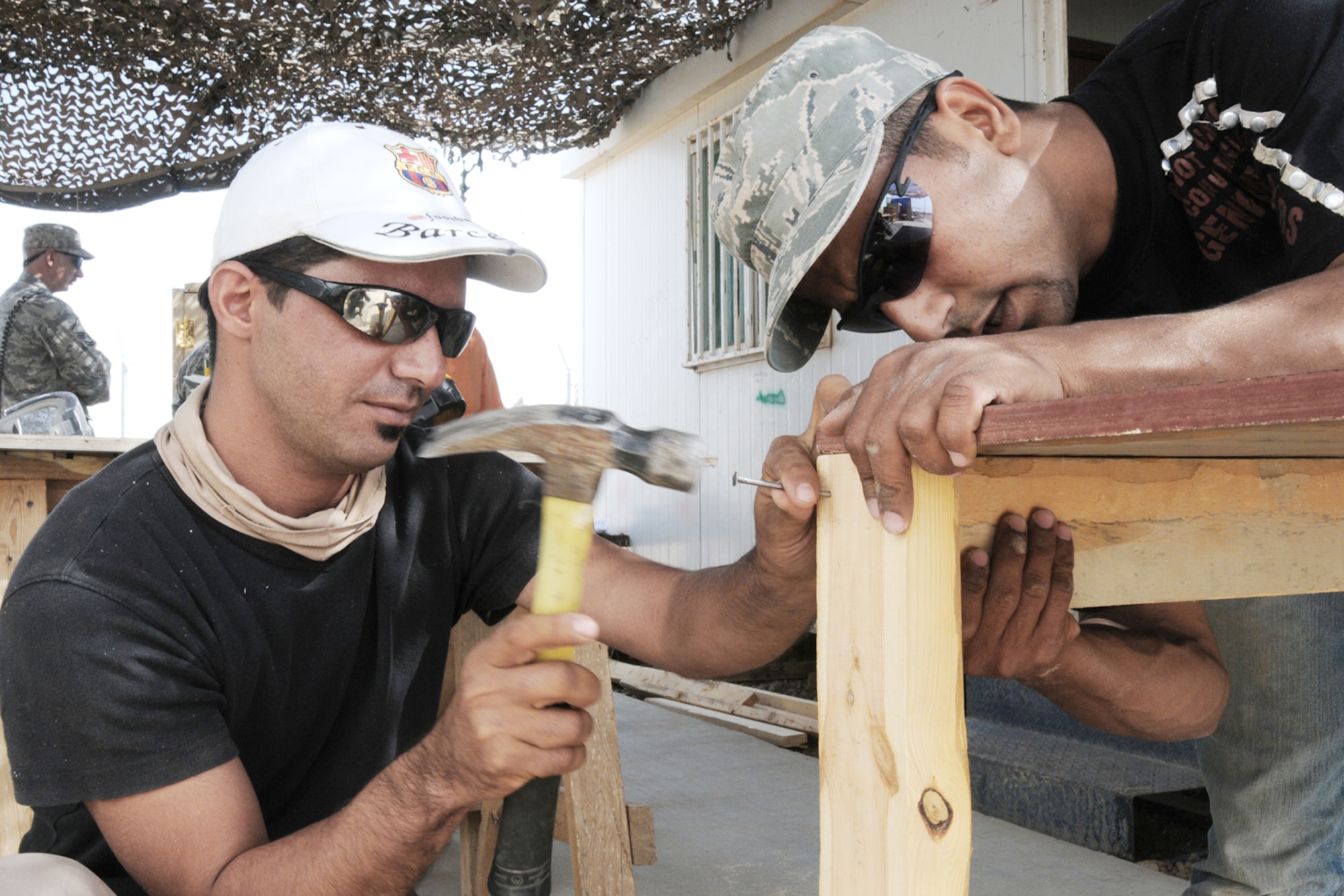 Iraqi workers Qusay Ahmad and Ahmad Hussein nail pieces of wood together to create a desk that will be used in a classroom for the Iraqi police counter explosive team Oct. 17, 2009, at Kirkuk Air Base, Iraq. Members of the 506th Expeditionary Civil Engineer Squadron works with local nationals who are employed by a local contractor on base to develop their skills which allow them to work and complete job orders. (U.S. Air Force photo/Staff Sgt. Daniel Martinez)