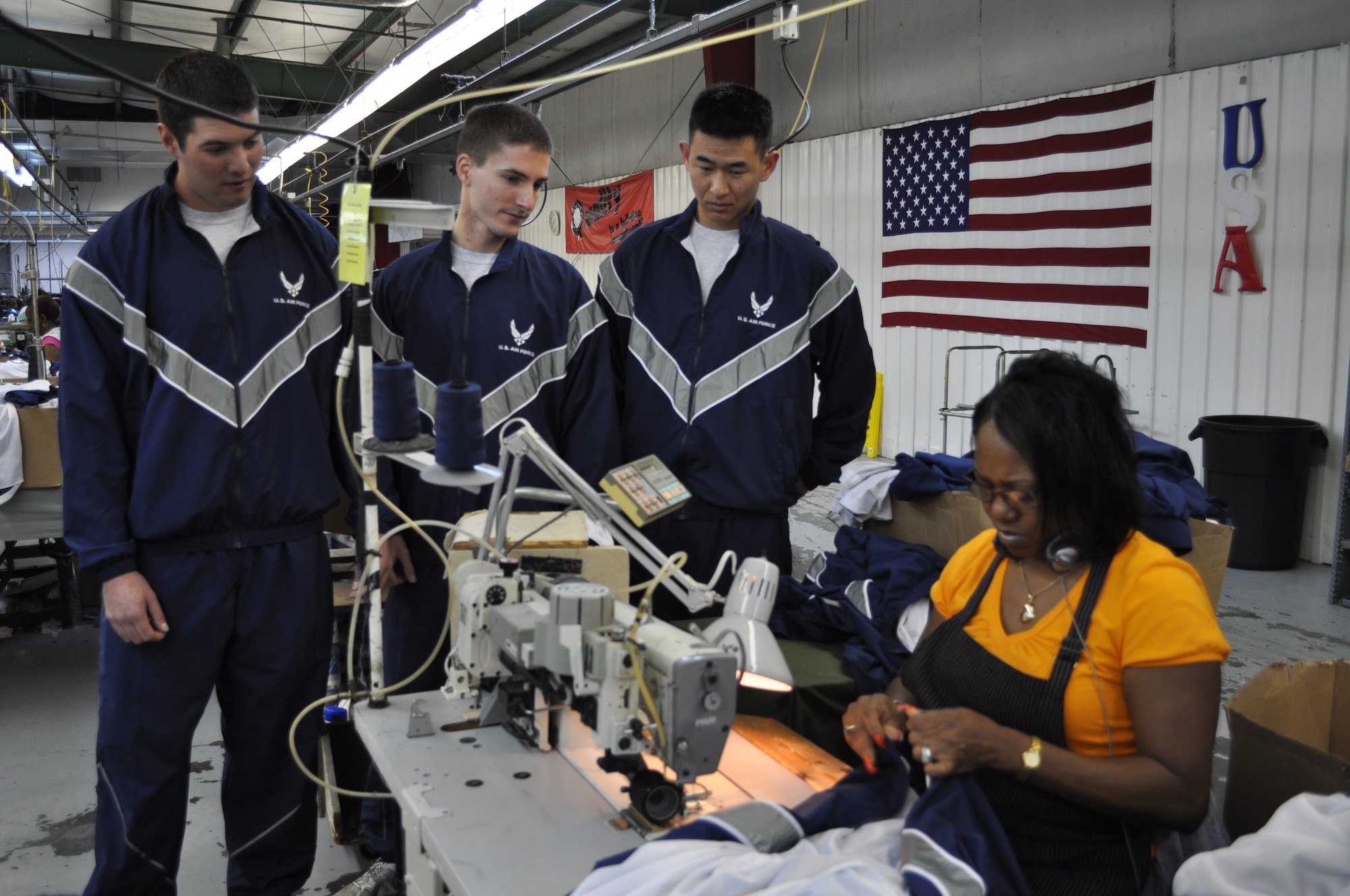 Sporting the  Air Force's new Improved Physical Training uniform, Lts.
Joseph Castro, Erik Svendsen and Andy Lee, 14th Operations Support Squadron,
Columbus AFB, Miss, watch as American Power Source seamstress Angela Smith
hems the anti-microbial liner into the new IPT uniform during a tour of the
facility Nov 3. (U.S. Air Force Photo/Sonic Johnson)