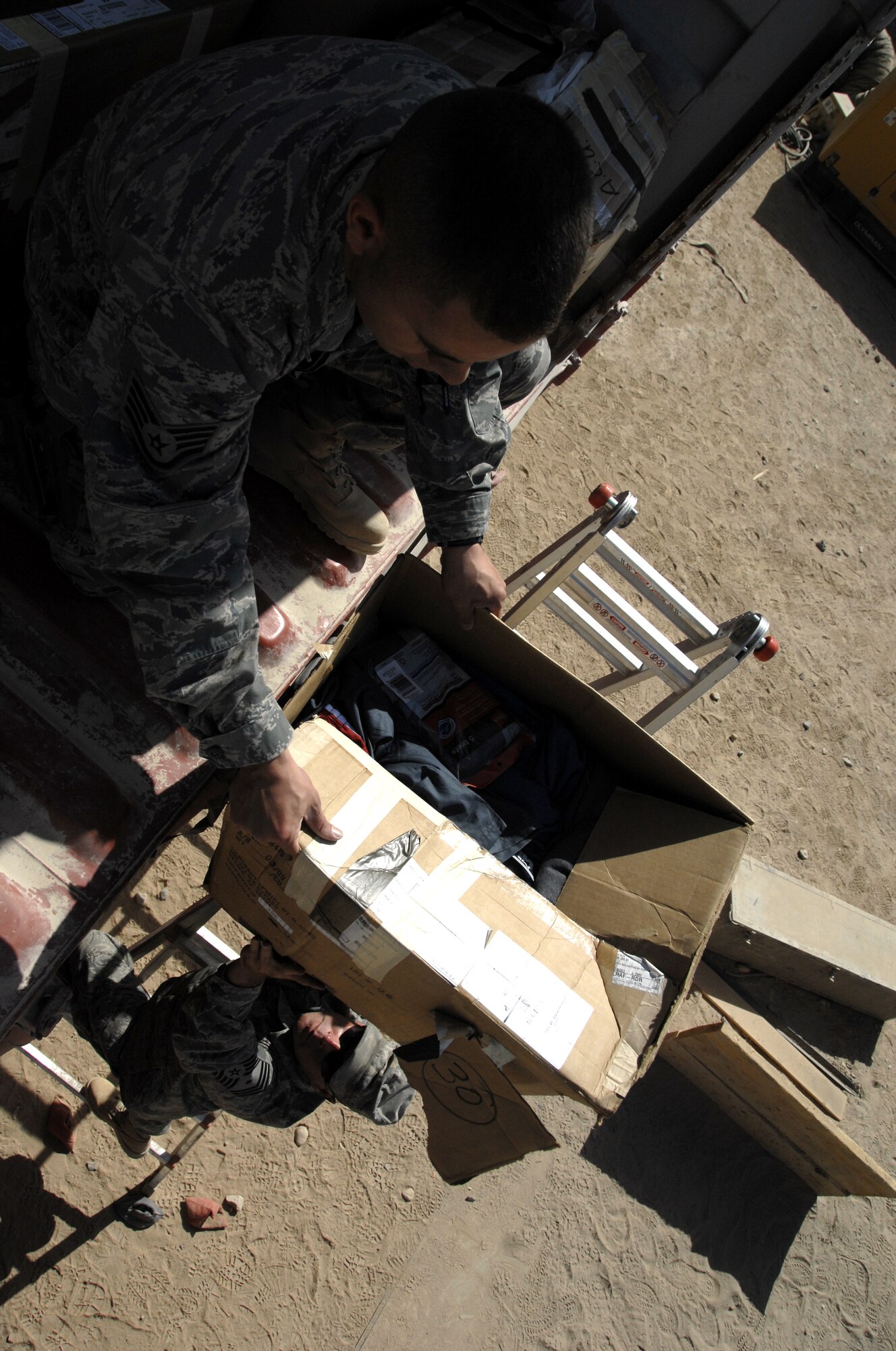 Chief Master Sgt. Michael Edwards hands Staff Sgt. Christopher Davidson a box of donated items to store until needed, here, Oct. 16. The son of Lt. Col. Bill Otter, who recently redeployed from Kandahar Airfield as the 772nd Expeditionary Airlift Squadron commander, put together an Eagle Scout project in which more than 400 DVDs and more than 300 books were donated to the 451st Air Expeditionary Wing.  Will Otter, a boy scout from Troop 23 in Cabot, Ark., sent 50 boxes filled with items donated from members within his community and Little Rock Air Force Base, Ark. In a letter he wrote to the wing he said collecting the donations was a challenging but rewarding process and hopes all will be excited to read and watch them just as much as he was to send them. (U.S. Air Force photo/Senior Airman Timothy Taylor)