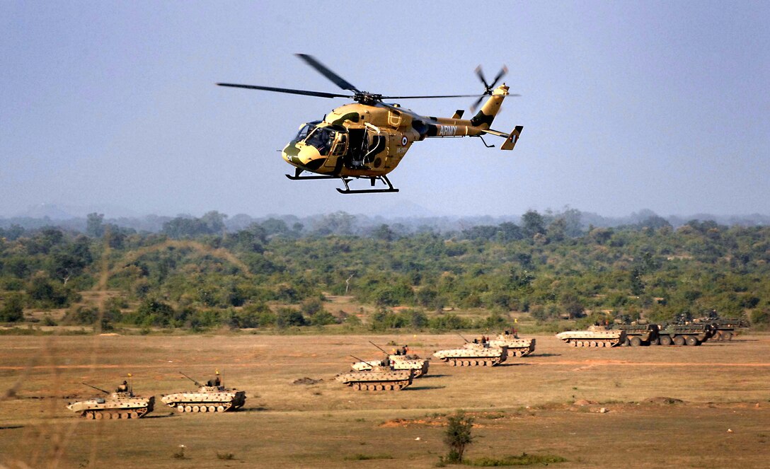 An Indian army helicopter flies over a field with both Soviet and U.S. military combat vehicles on a firing line. during a joint exercise with soldiers from the 2nd Squadron, 14th Cavalry Regiment, based out of Hawaii. The exercise was a culmination of two weeks of joint training at Camp Bundela, India. 