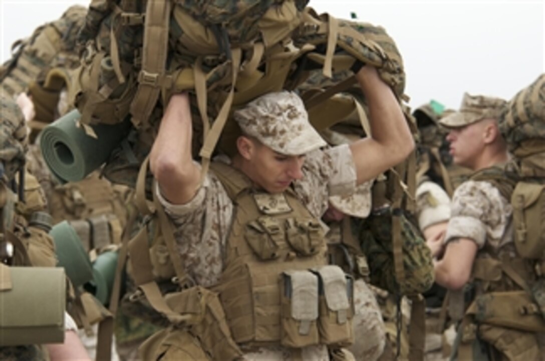 U.S. Marine Corps Lance Cpl. Brandon Focer heaves his pack over his head as he prepares to board a landing craft utility to embark aboard the amphibious assault ship USS Nassau (LHA 4) in Radio Island, N.C., on Oct. 27, 2009.  Focer is assigned to Charlie Company, 2nd Platoon, 24th Marine Expeditionary Unit.  The Nassau and 24th Marine Expeditionary Unit are participating in a composite unit training exercise designed to provide realistic training environments for U.S. naval forces that closely replicate the operational challenges routinely encountered during military operations worldwide.  