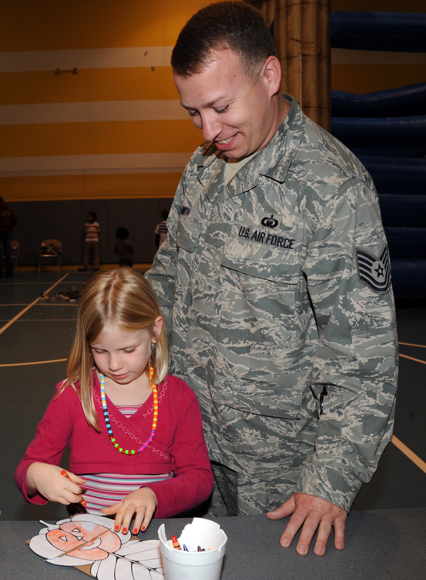 Tech. Sgt. James Smith, 22nd Air Refueling Wing chapel, watches his daughter, Kyleigh, 6, color a pumpkin cutouts Nov. 2, 2009, at the youth center during the annual Family Fun and Feast at McConnell Air Force Base, Kan. (U.S. Air Force photo/Staff Sgt. Amanda Currier)