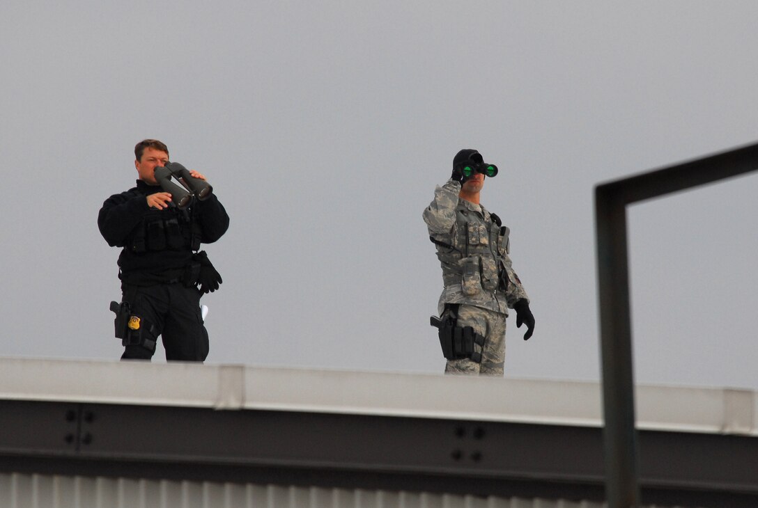 Staff Sgt. Anthony Rook (right), security forces member at the 115th Fighter Wing in Madison, Wis., along with a Secret Service agent scan for potential threats prior to and during a presidential visit Nov. 4, 2009.  President Barack Obama landed at the Air National Guard base on his way to give a speech at Madison's James Wright middle school about education reform.  President Obama's visit marks the first time that a sitting president has visited the base. (U.S. Air Force Photo by Master Sgt. Dan Richardson)