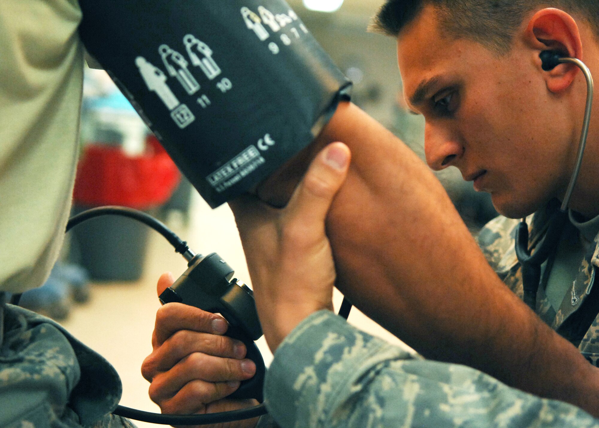 JOINT BASE BALAD, Iraq -- Staff Sgt. Christopher Hipsher, 332nd Expeditionary Communications Squadron small computer technician, uses a specialized cuff to check another Airman’s blood pressure at the Air Force Theater Hospital here Oct. 22, 2009. Sergeant Hipsher is an emergency medical technician volunteer and is state certified in Hawaii. (U.S. Air Force photo/ Senior Airman Christopher Hubenthal)