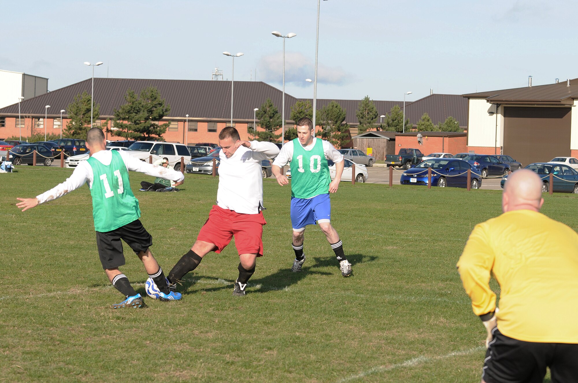 RAF MILDENHALL, England -- Nick Giannopoulos (red shorts), 352nd Maintenance Squadron, tackles Daniel Crane (11), 100th Security Forces Squadron, while Daniel Baker (10), looks on during an intramural soccer match Nov. 4. The 100th SFS took the game 3-2 at the Hardstand Fitness Center.  (U.S. Air Force photo/Senior Airman Thomas Trower)
