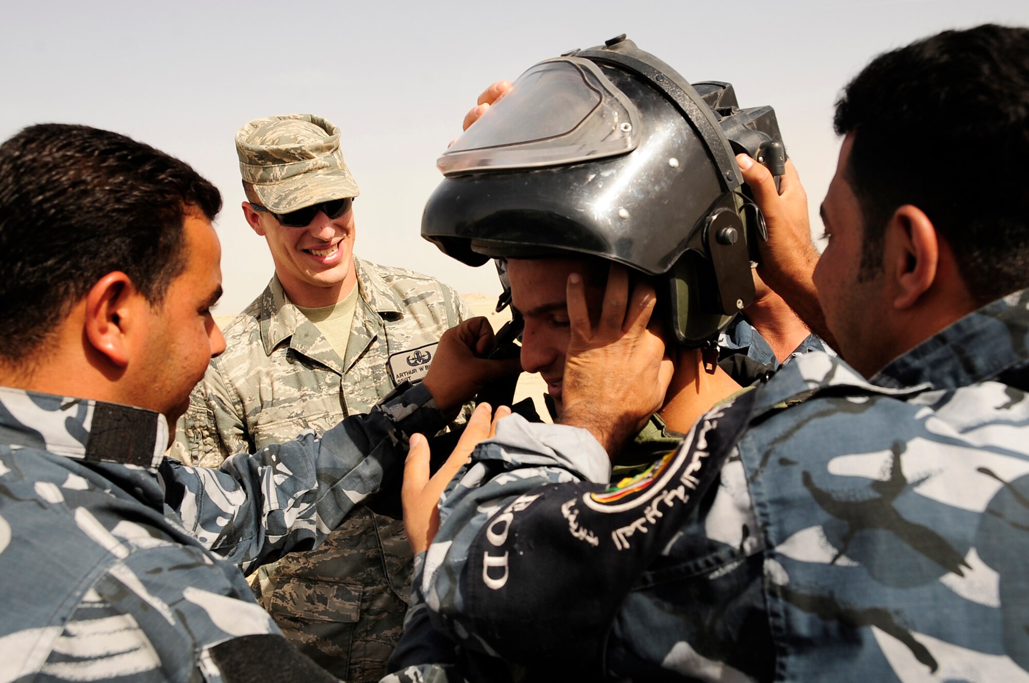 FORWARD OPERATING BASE CEDAR, Iraq -- U.S. Air Force Staff Sgt. Arthur Bigelow, explosive ordinance disposal (EOD) technician, 407th Expeditionary Civil Engineer Squadron, assists Iraqi Police EOD technicians get a team member into a bomb suit during a training scenario conducted by the Air Force EOD members here, Nov. 4, 2009. The training was a part of a six week course offered to the Iraqi Police to better help them understand the technicalities of EOD that would further aid in the transition of troops scheduled to withdraw from Iraq in 2011. Sergeant Bigelow is deployed here from Fairchild Air Force Base, Wash. (U.S. Air Force photo by Senior Airman Tony R. Ritter)