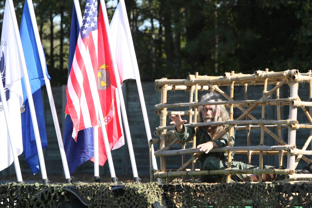 A man was held in a wooden cage reaches for crowds asking for help to simulate a prisoner of war. The POW rode on a trailer with a sign that read "Help us bring them home," during the Veterans Day Parade in Jacksonville, N.C. Nov. 7.