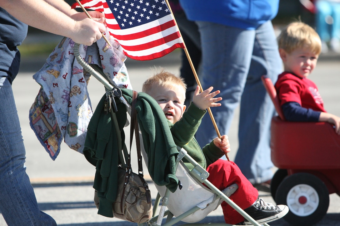 A boy being pushed in a stroller by his mother waved an American flag at the crowds as they walked in the Veterans Day Parade on Western Boulevard in Jacksonville, N.C. Nov. 7.