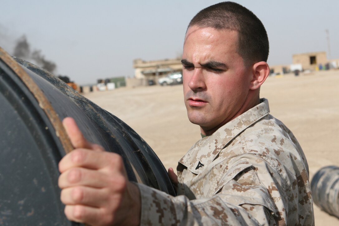 Lance Cpl. Ryan W. Pollock, a base safety clerk with Combat Logistics Regiment 27 (Forward), stacks an empty drum at the Hazardous Material Lot, aboard Camp Al Taqaddum, Iraq, Nov. 6, 2009.  The drum will be used to transport hazardous material to a proper disposal site. (U.S. Marine Corps photograph by Cpl. M. M. Bravo)