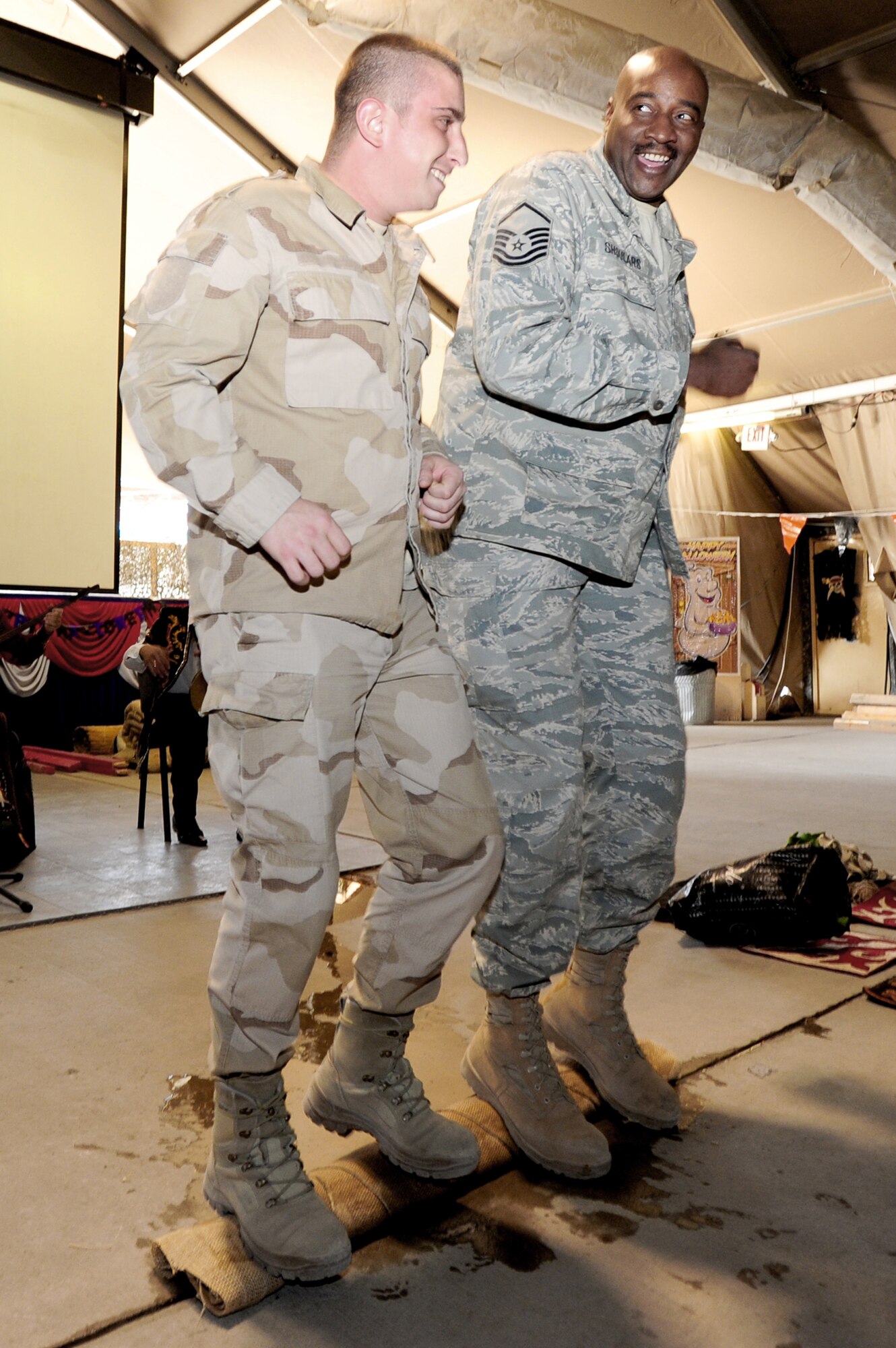 Master Sgt. John Shoulars and a Polish airman "dance" on a carpet to remove water during a Kyrgyz Culture Day at the Transit Center at Manas, Kyrgyzstan, recently.  Sergeant Shoulars is the sustainment flight chief for the 376th Expeditionary Force Support Squadron. (U.S. Air Force photo/Senior Airman Steele Britton)