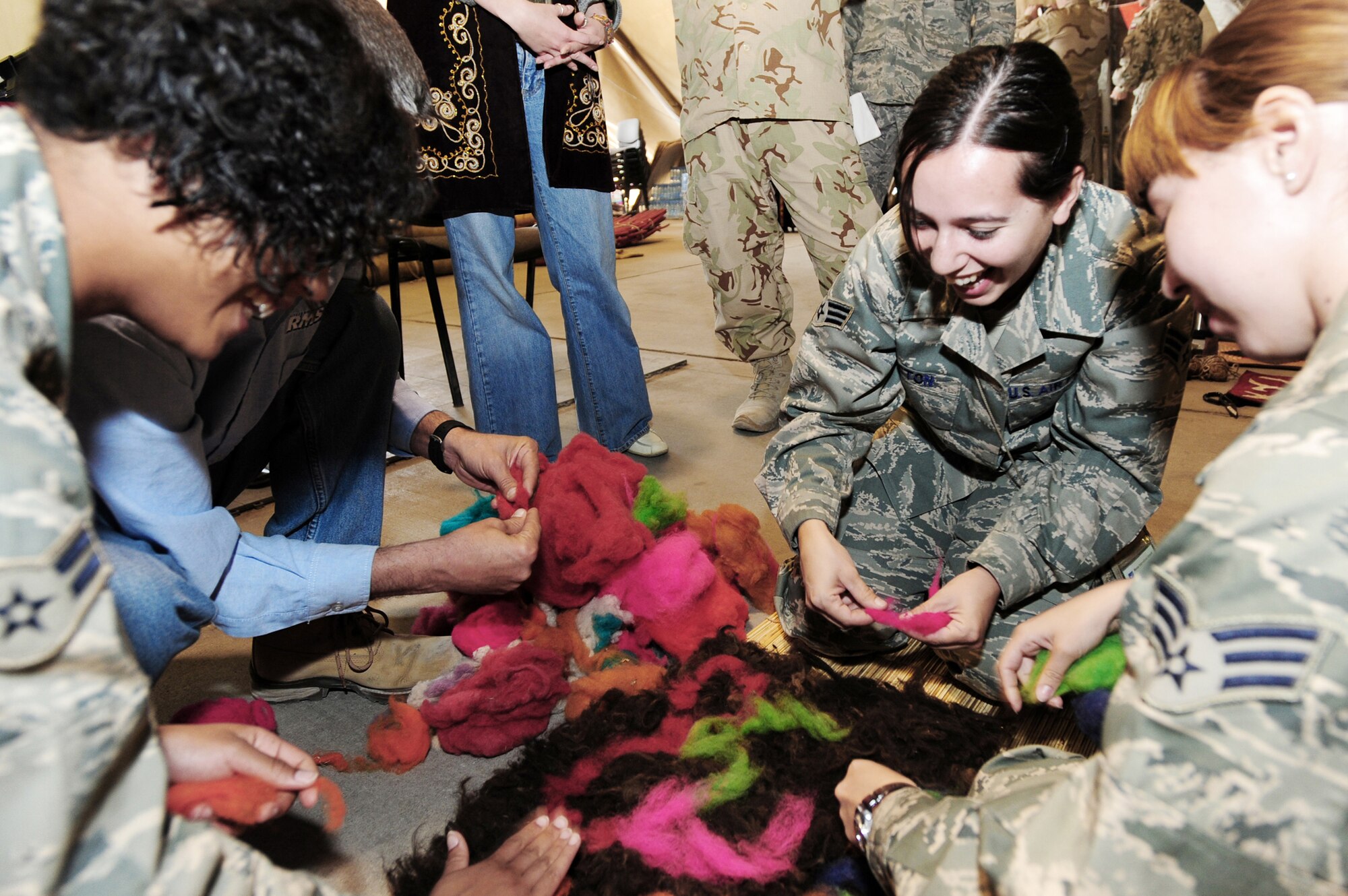 Senior Airmen Alaina Acton (center) and Maria Gates (right) design a carpet with Airman 1st Class Mariah Ham (left) in the Kyrgyz tradition of rugmaking during Kyrgyz Culture Day at the Transit Center at Manas, Kyrgyzstan recently. (U.S. Air Force photo/Senior Airman Steele Britton)