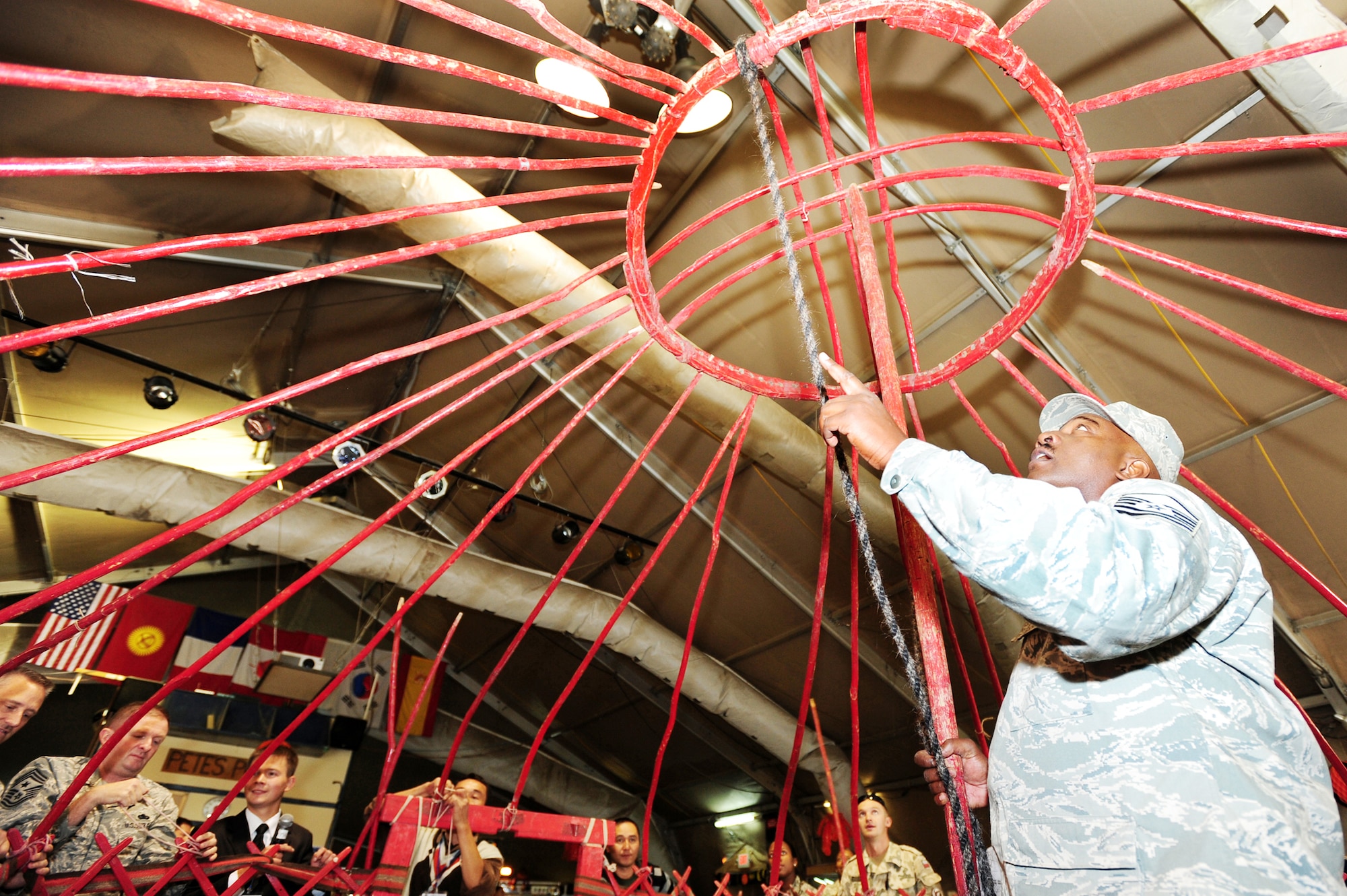 Master Sgt. John Shoulars, 376th Expeditionary Force Support Squadron sustainment flight chief, holds up the tyundyuk while others connect the roof of a traditional Kyrgyz yurt during Kyrgyz Culture Day at the Transit Center at Manas, Kyrgyzstan. The tyundyuk is symbolic of Kyrgyzstan and is the center of the country's flag. (U.S. Air Force photo/Senior Airman Steele Britton)
