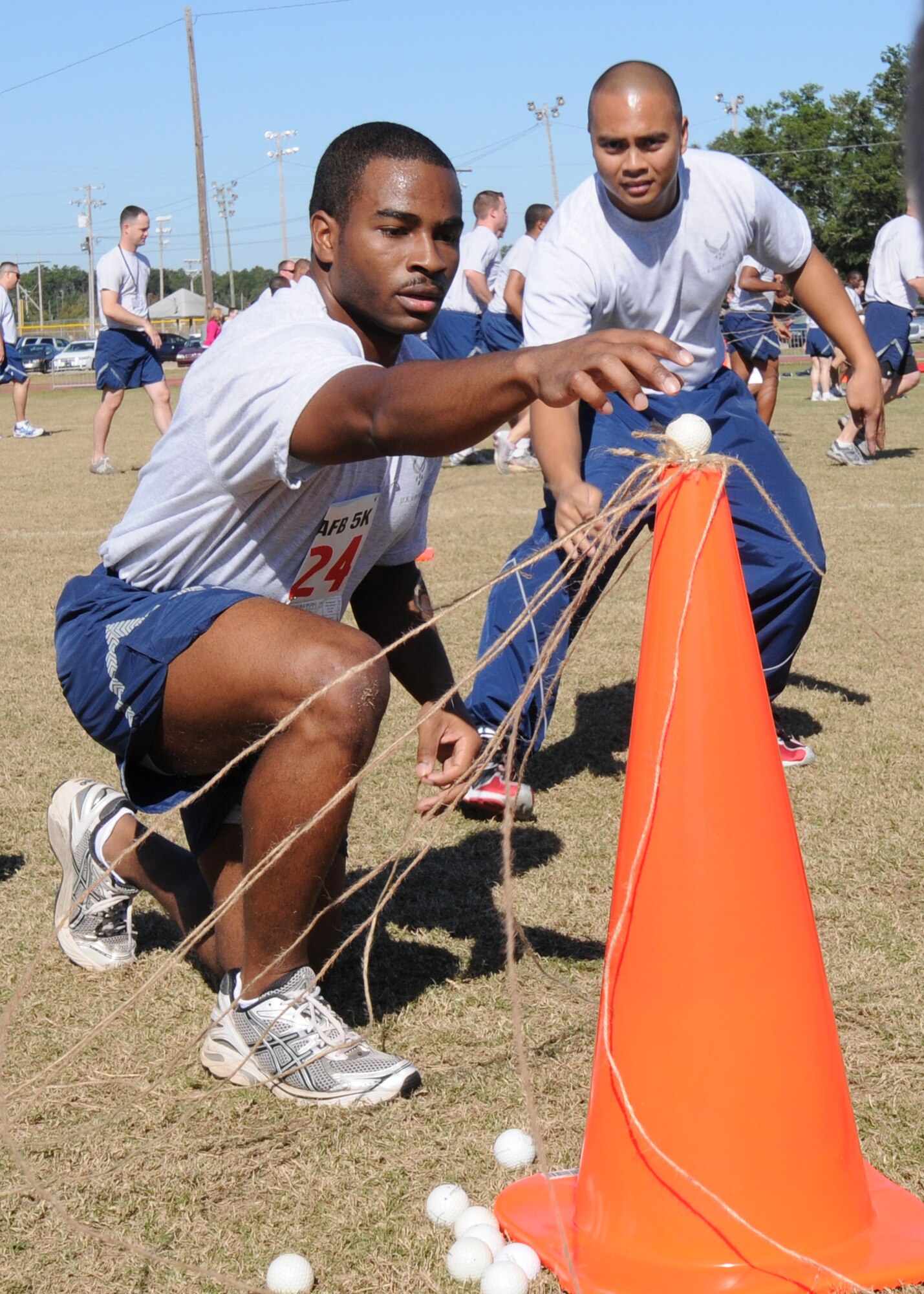 The team leader for a 53rd Wing team ensures the golf ball is balanced for knocking it off the cone and beginning again during a team work activity at Eglin’s Wingman Day, Nov. 5. The exercise had team members move a golf ball with strings from one cone to another.  Teams had to work together and communicate to keep the ball from dropping.  (Air Force photo/Samuel King Jr.)