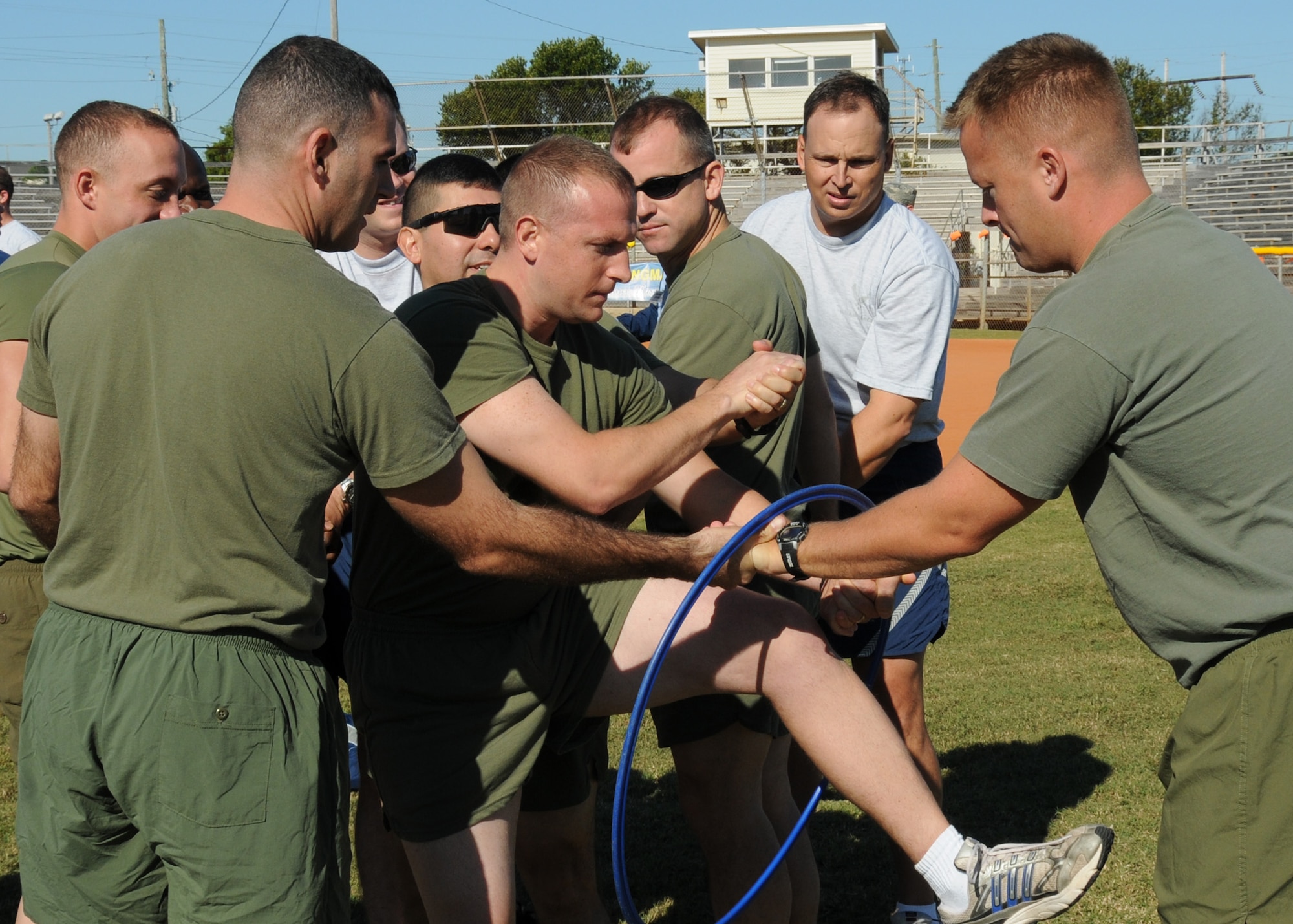 A team of Airmen and Marines work together to move their team through a small hoop, during an activity at the Eglin Wingman Day, Nov. 5.  Wingman Day was held to enhance personal wellness, increase unit cohesion and the installation community’s ability to care for itself, for one another and to accomplish the mission through activities that promote high-level team functioning and decrease “risk factor” behaviors.  (Air Force photo/Samuel King Jr.)