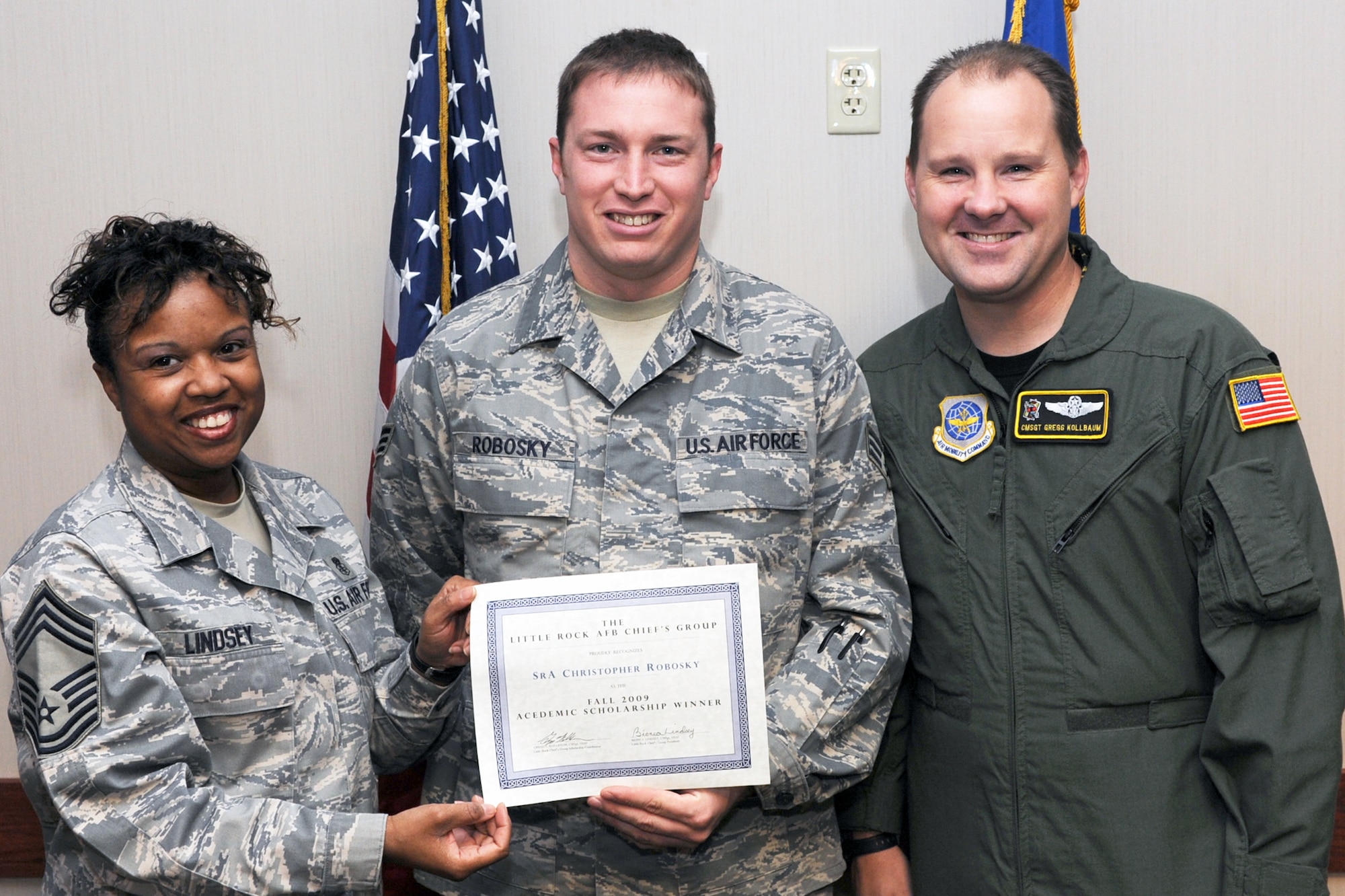 Senior Airman Christopher Robosky, 19th Operations Group, intelligence analyst, receives a Chief's Group scholarship Nov. 4 from Chief Master Sgt. Bionca Lindsey, 19th Medical Group superintendent; and Chief Master Sgt. Gregg Kollbaum, 53rd Airlift Squadron superintendent; at the Hercules dining facility. (U.S. Air Force photo by Senior Airman Ethan Morgan)