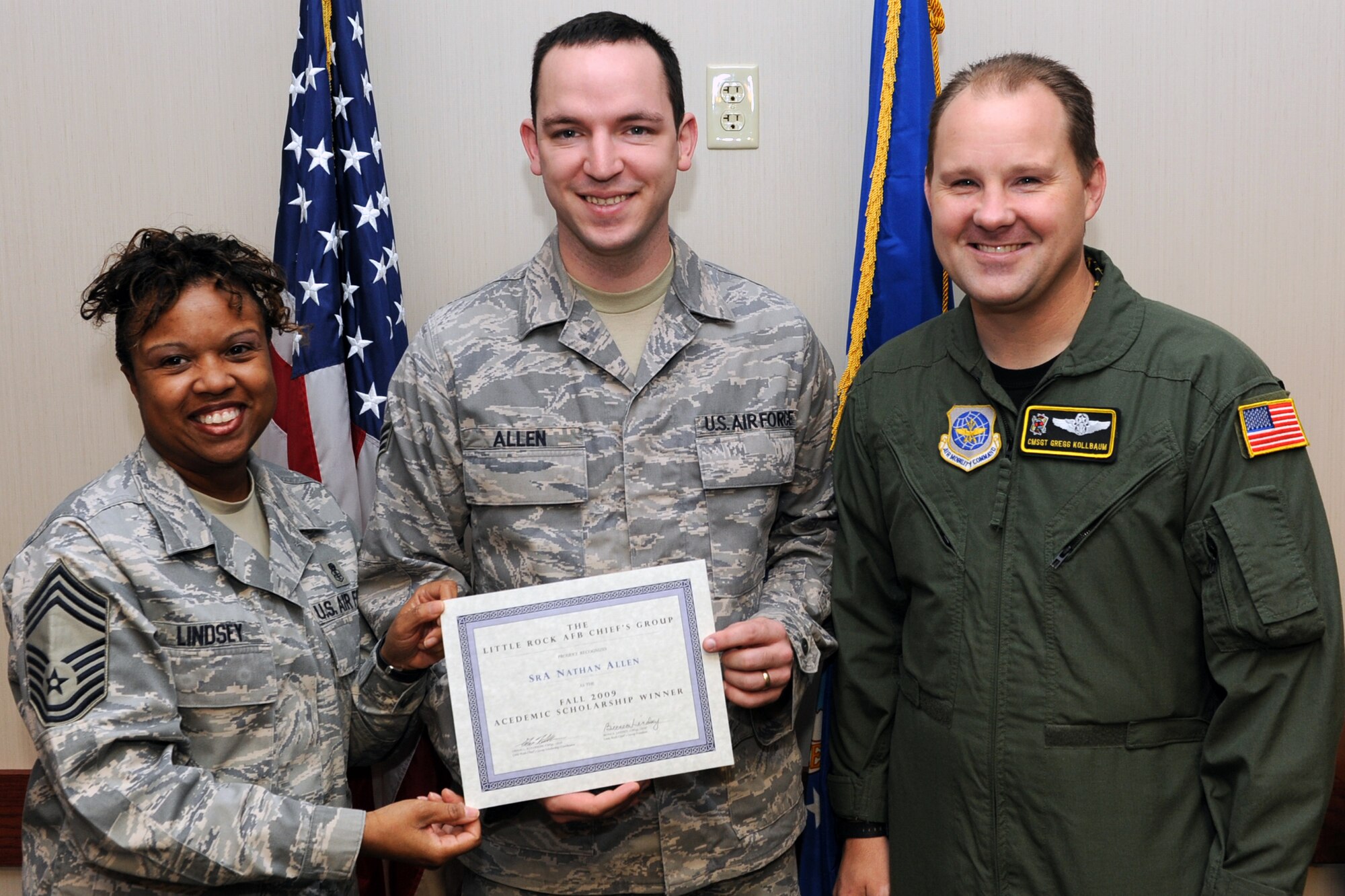 Senior Airman Nathan Allen, 19th Airlift Wing Public Affairs photographer, receives a Chief's Group scholarship Nov. 4 from Chief Master Sgt. Lindsey, 19th Medical Group superintendent, and Chief Master Sgt. Gregg Kollbaum, 53rd Airlift Squadron superintendent, at the Hercules dining facility. (U.S. Air Force photo by Senior Airman Ethan Morgan)
