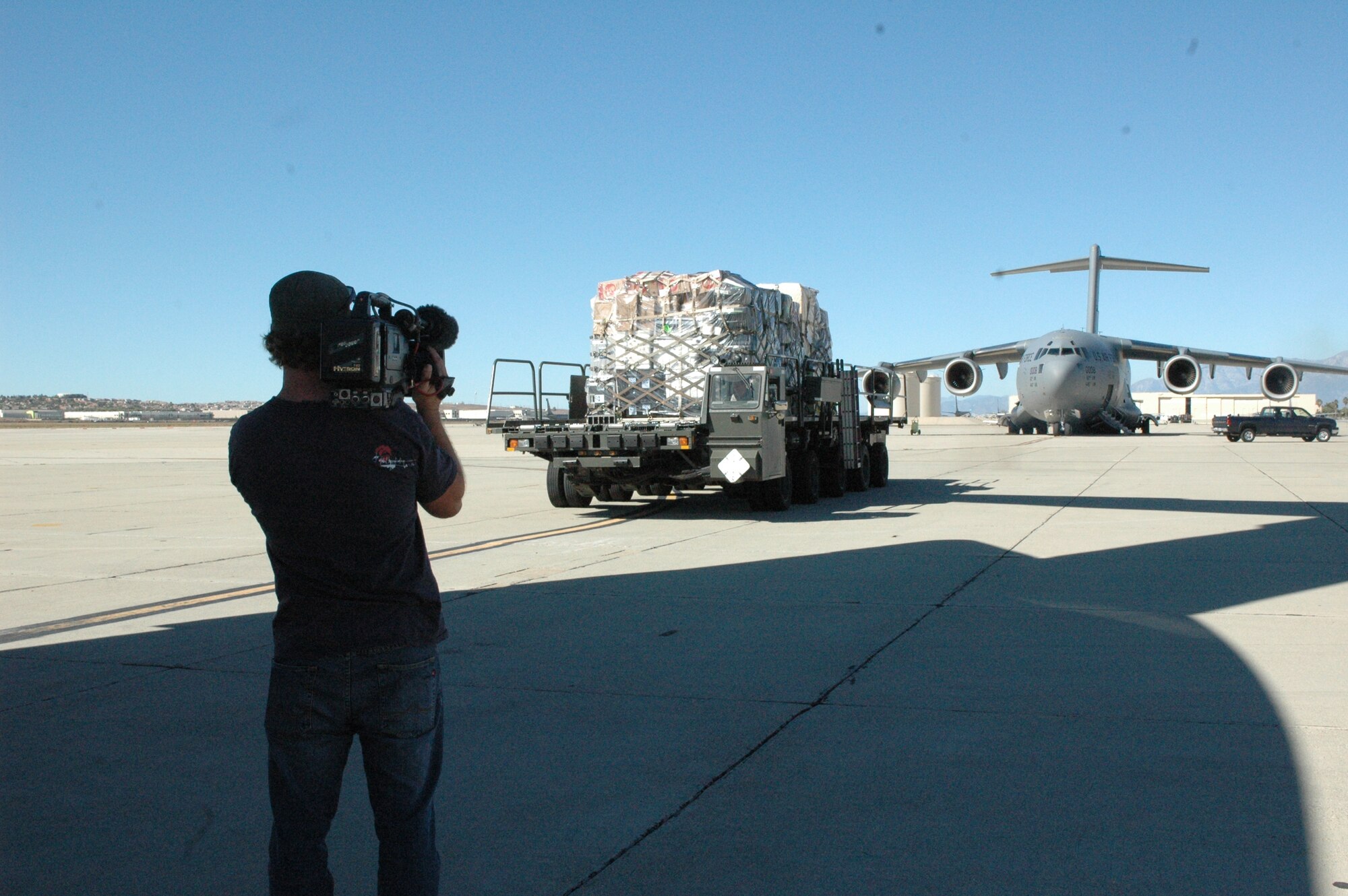 A Fox Sports videographer films the loading of cargo into a C-17 that was tasked for a mission taking a Fox Sports crew to Afghanistan to perform a morale show for the troops. (U.S. Air Force photo/2nd Lt. Holly Hess)
