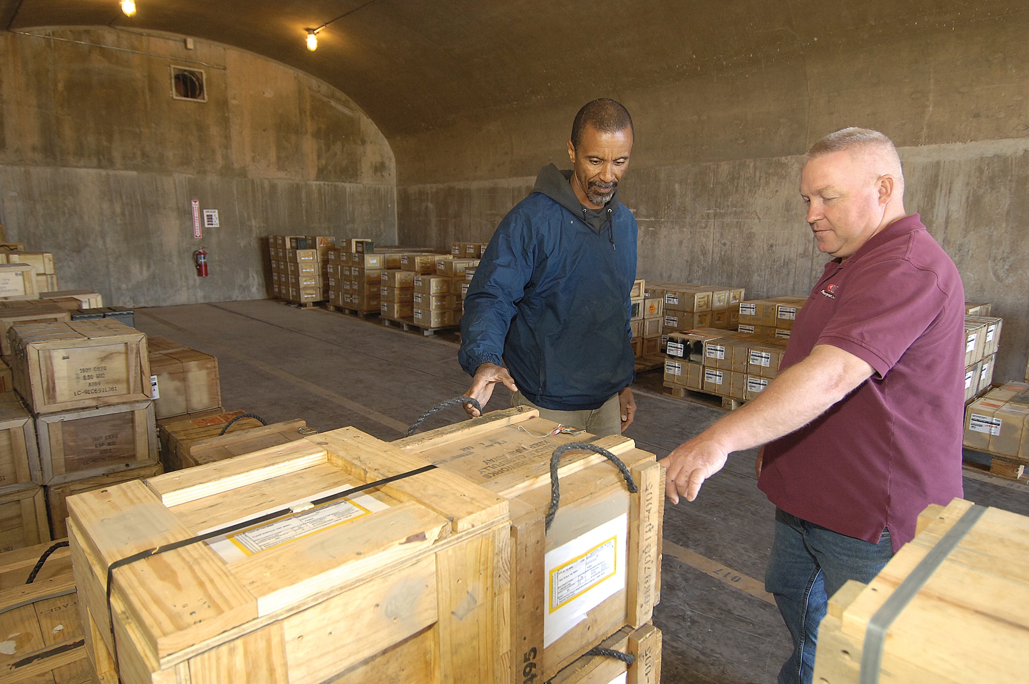 Lawrence Peterson, left, and Jeff Appelman, 72nd Logistic Readiness Squadron munitions operations, inspect crates of small arms ammunition secured in an earth-covered, reinforced concrete munitions igloo.  Most functions the munitions technicians perform in the base munitions storage area require two people for safety. (Air Force photo by Margo Wright)