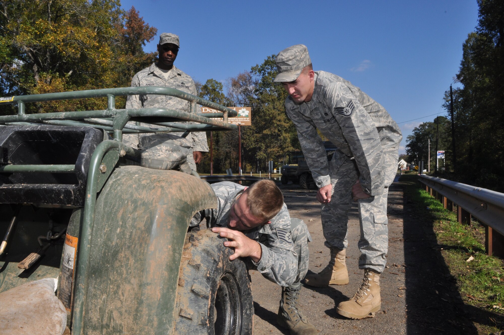 Staff Sgt. Corey Ricker checks the axle of an all-terrain vehicle as Staff Sgt. Davis McClain and Master Sgt. Michael Jordan look on during ongoing sandbagging operations near Hickory Ridge Drive in Bossier City, La., November 4, 2009. The Airmen are part of effort to keep a neighborhood from flooding after abnormal amounts of rain fell on the Red Chute Bayou area. Both Sergeants Ricker and McClain are vehicle and vehicular maintenance journeymen with the 2nd Logistics Readiness Squadron at Barksdale Air Force Base La., and were responsible for keeping ATVs that transported sand bags operational. Sergeant Jordan is with the 2nd Force Support Squadron and was the Senior NCO on duty at the time. His duties included ensuring the safety of Barksdale assets and personnel. (U.S. Air Force photo/Tech. Sgt. Jeff Walston)