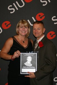 EDWARDSVILLE, Ill. -- Col. August "Gus" Schalkham, Air Combat Command Public Affairs Individual Mobilized Augmentee, and his wife, Tammy, accept the Southern Illinois University Edwardsville Athletic Hall of Fame plaque Oct. 24. The university inducted Colonel Schalkham into the Hall of Fame for his many athletic achievements as a student and coach. (Courtesy photo)